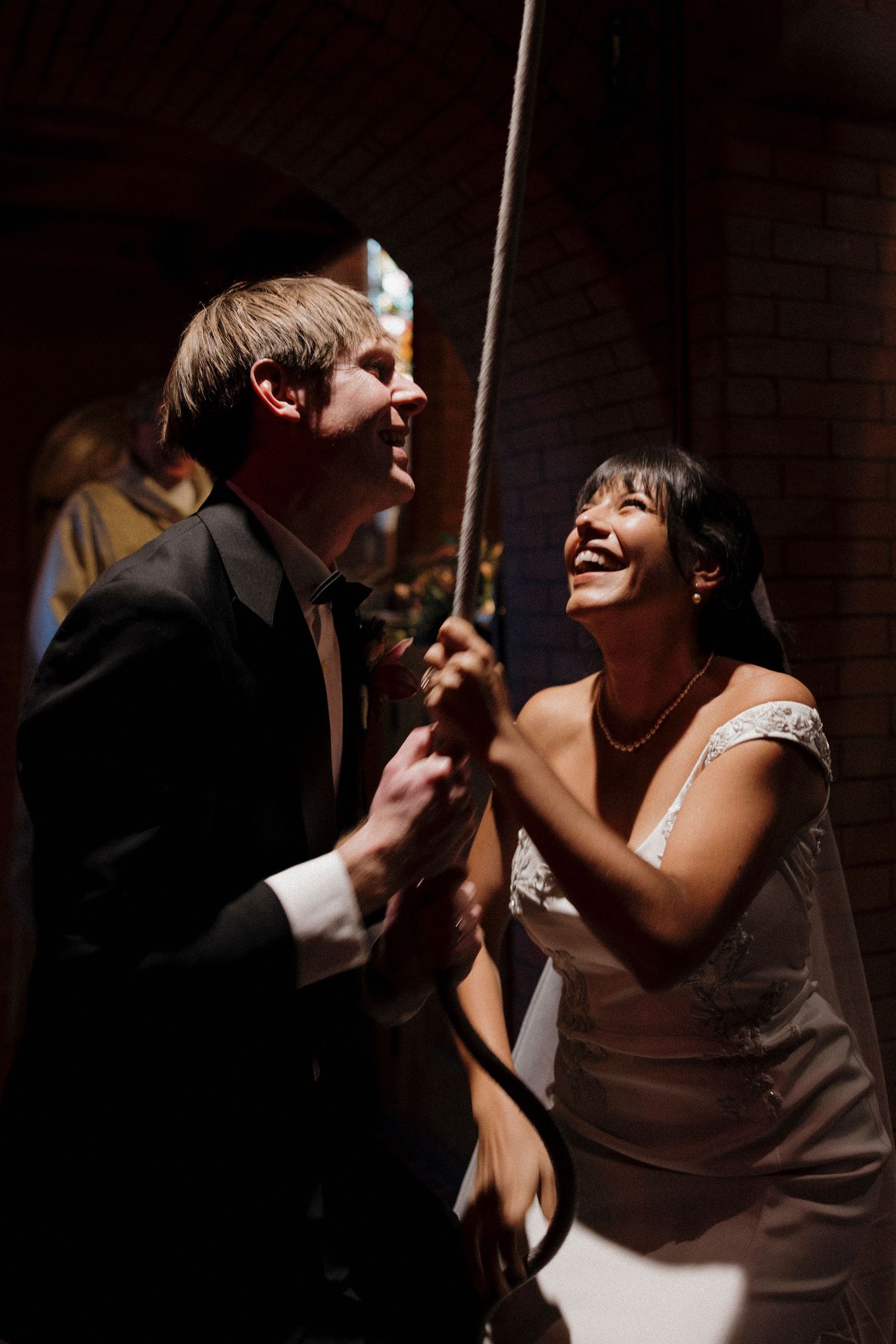 Wedding couple dances and laughs together in dramatic lighting.