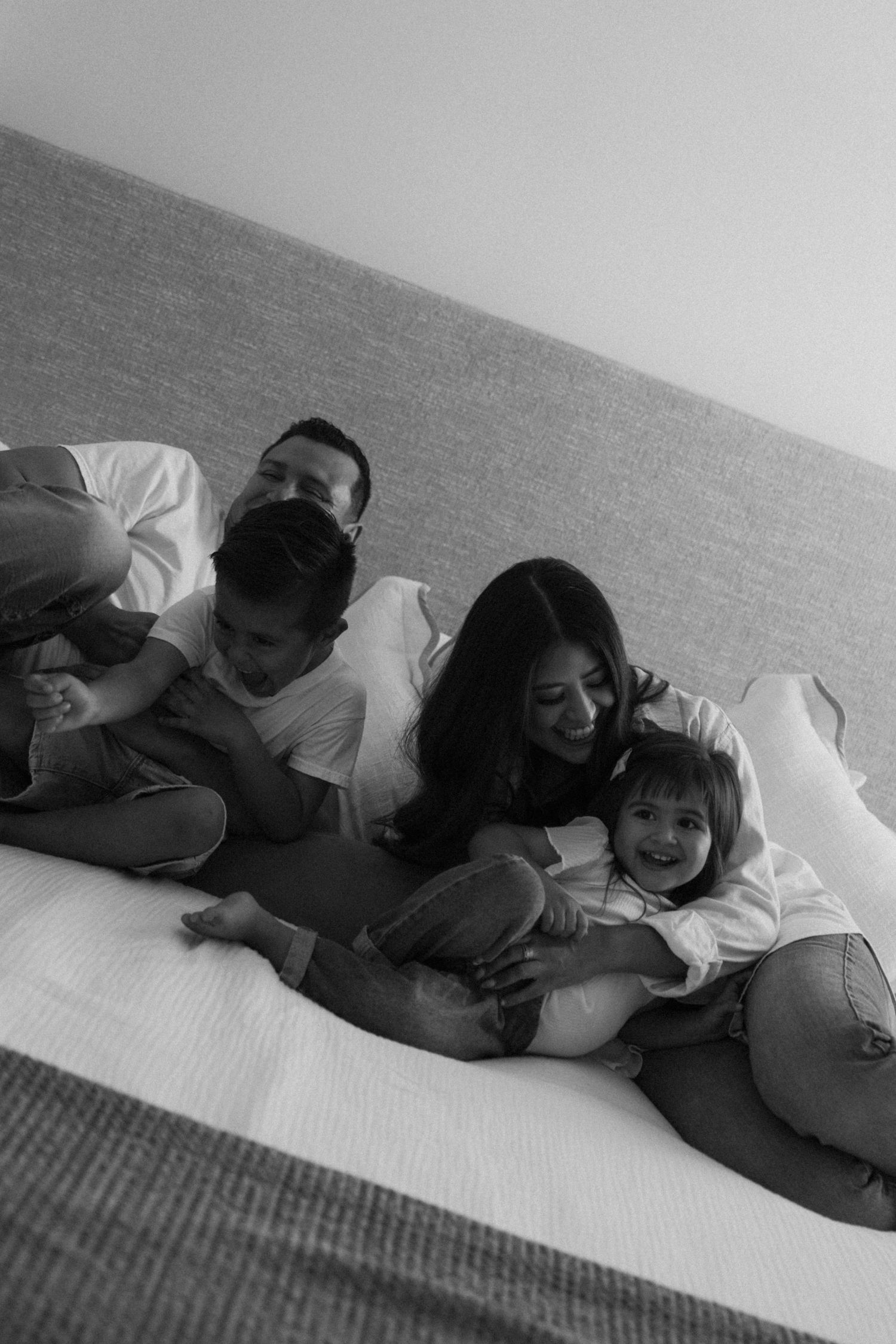 Candid black and white photo of family members cuddling on couch.