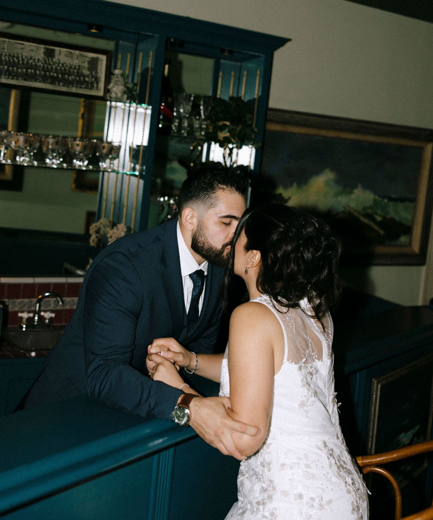 Intimate dance sequence between couple in formal attire near wooden furniture.