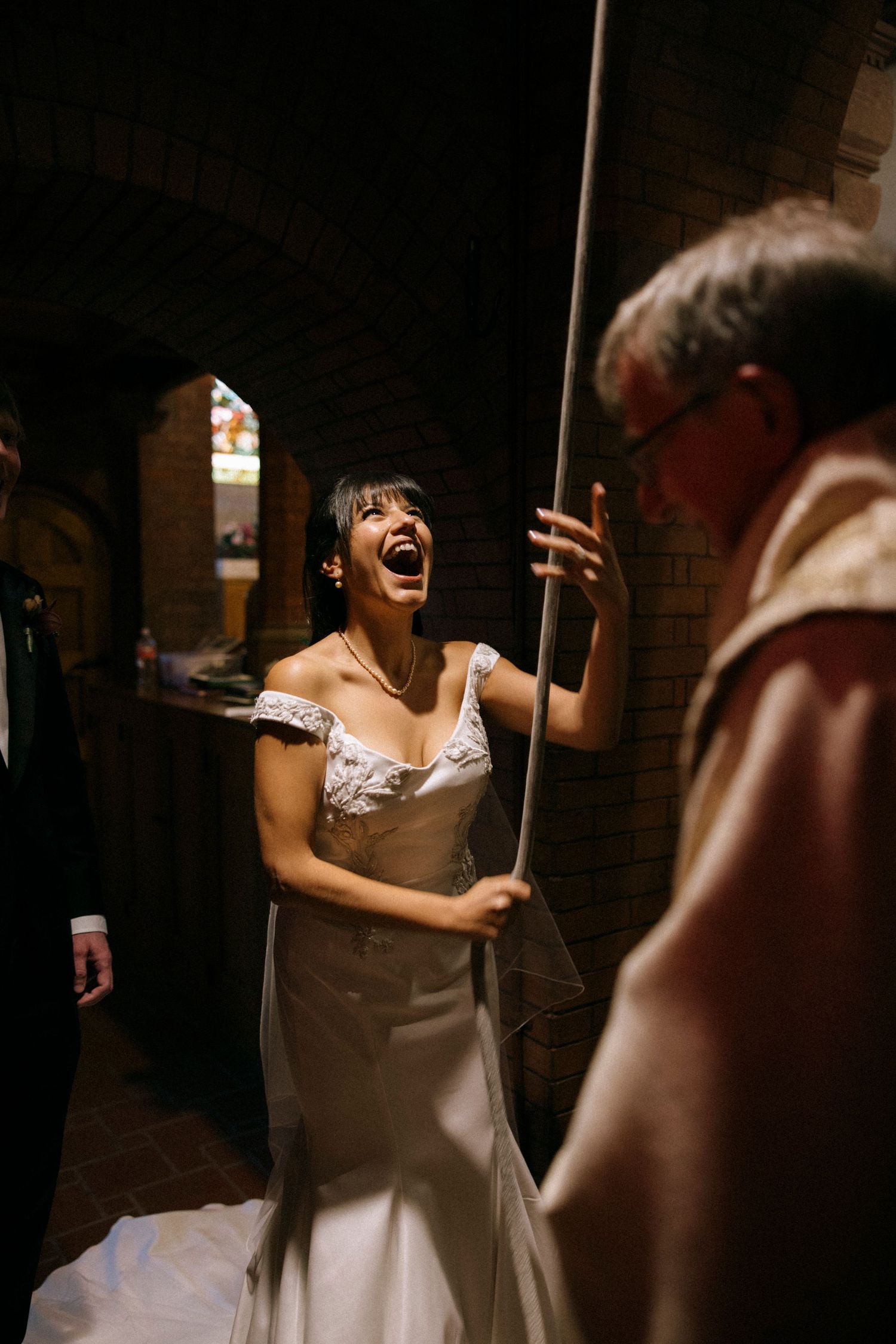 A bride in white dress laughs joyfully during wedding celebrations.