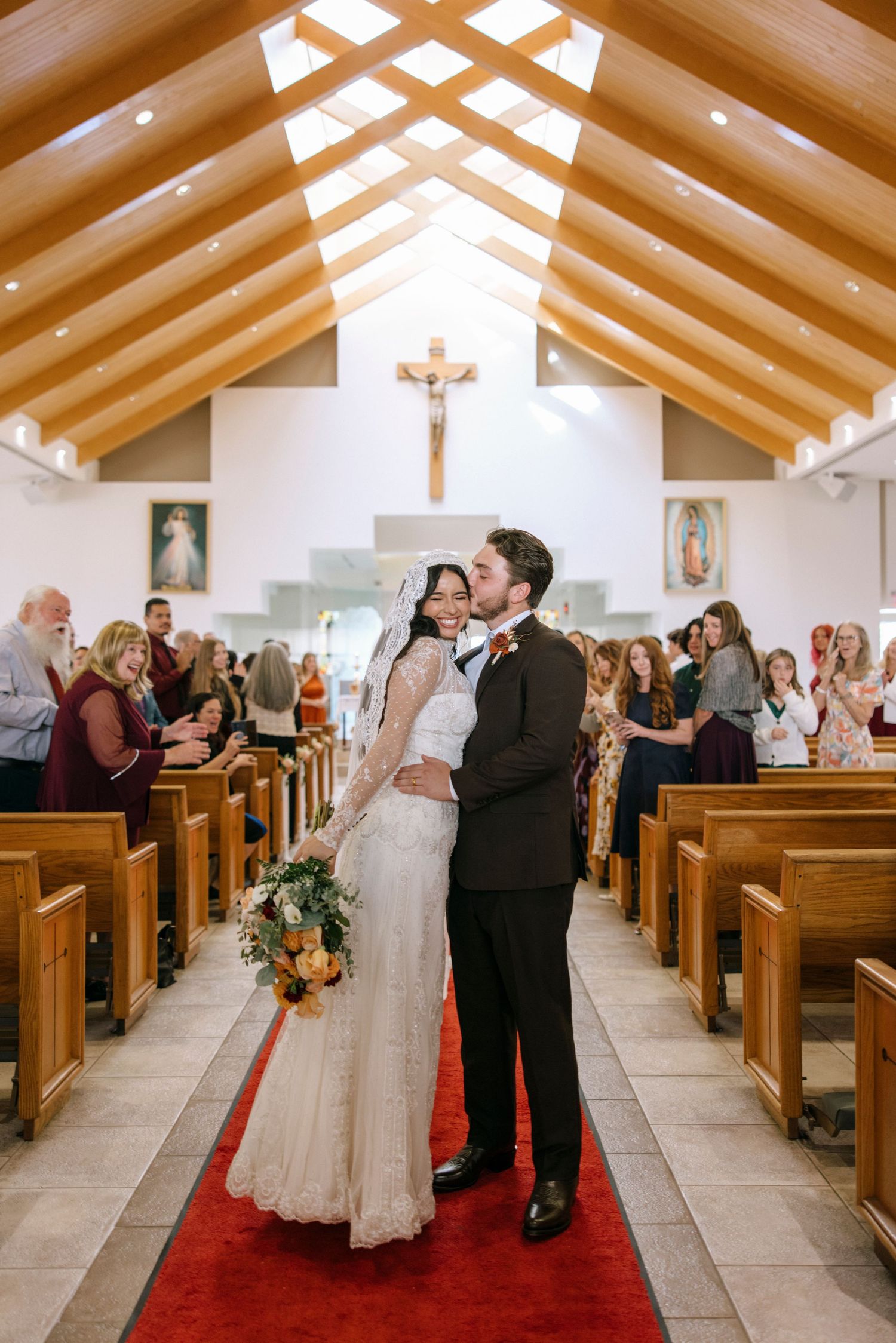 Wedding ceremony in bright church with wooden beams and guests seated in pews.