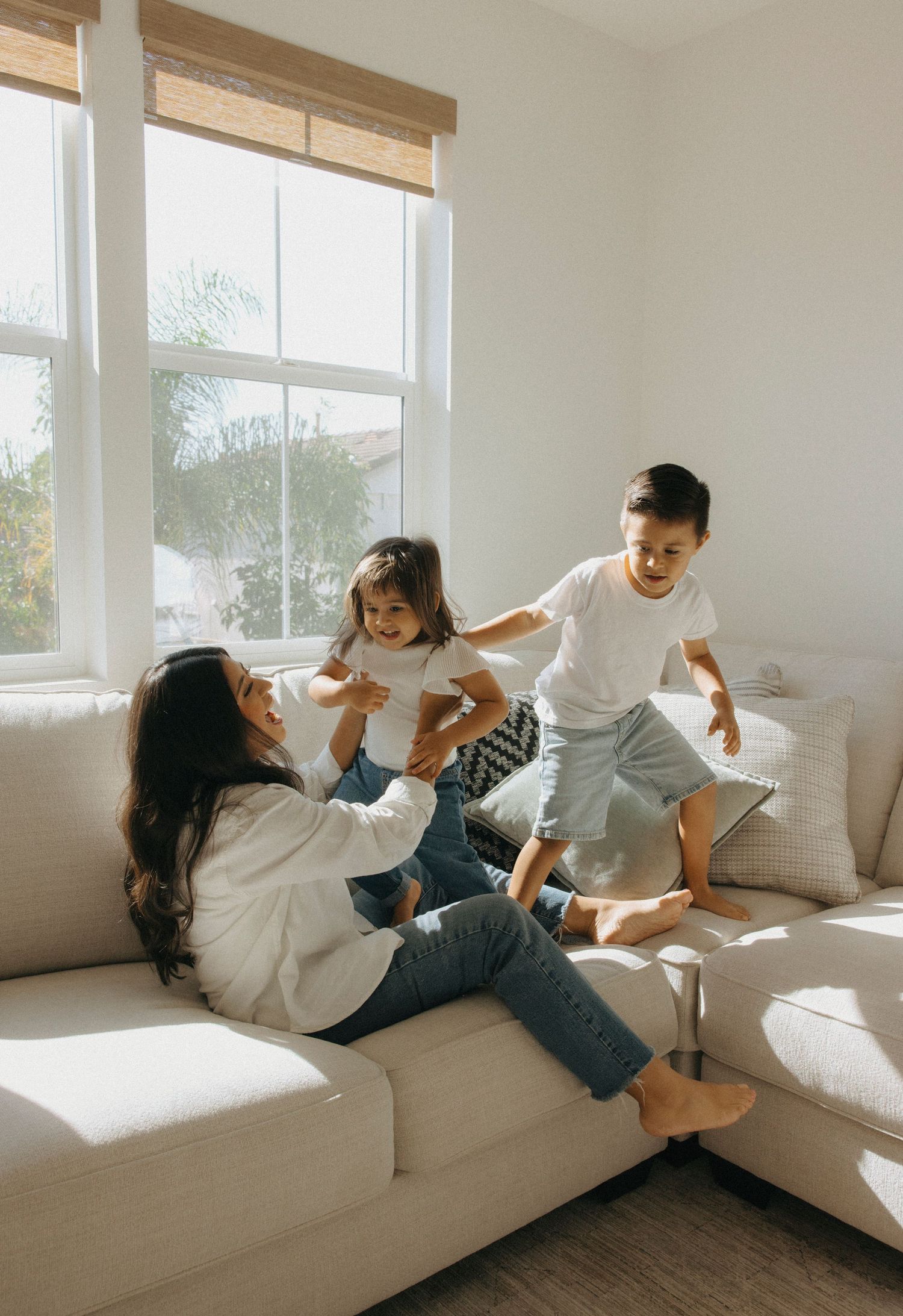 Family enjoying quality time together on a sunlit white couch.