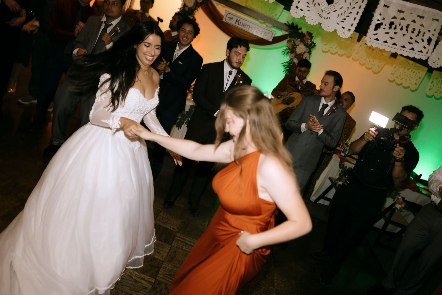 Wedding guests dancing together at a reception with a mix of formal attire and colorful dresses.