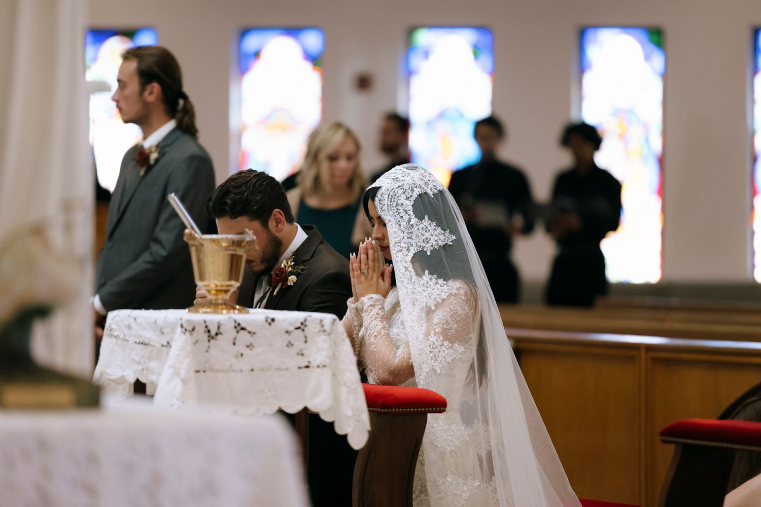 Church wedding ceremony with stained glass windows in background.