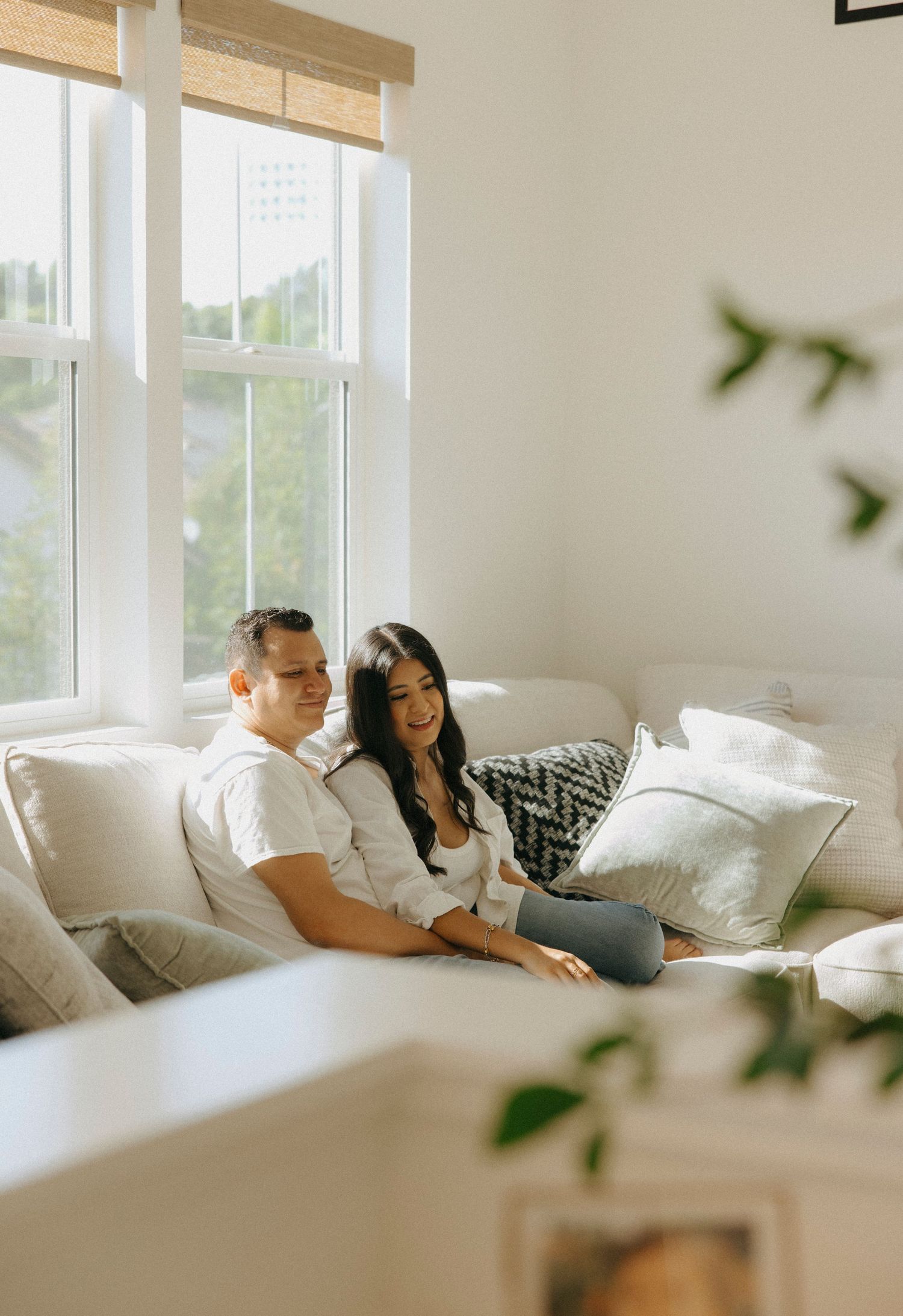 A couple relaxes together on a white couch in a bright, modern living room.