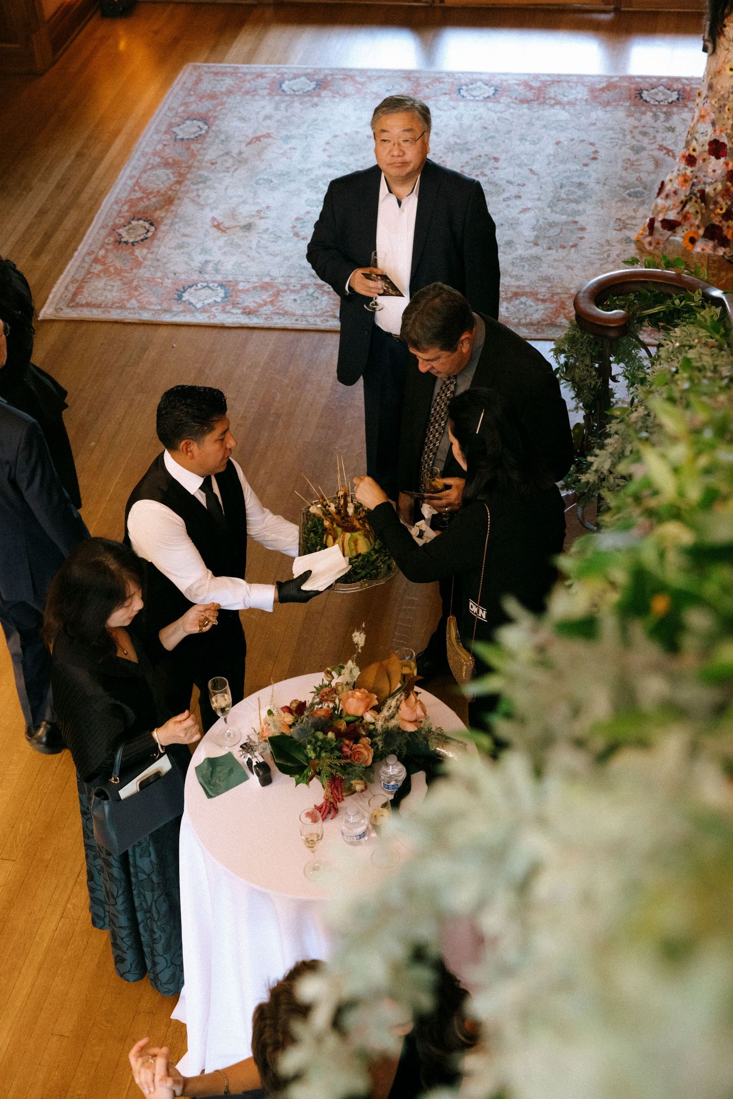 Event staff preparing food service at elegantly decorated tables.