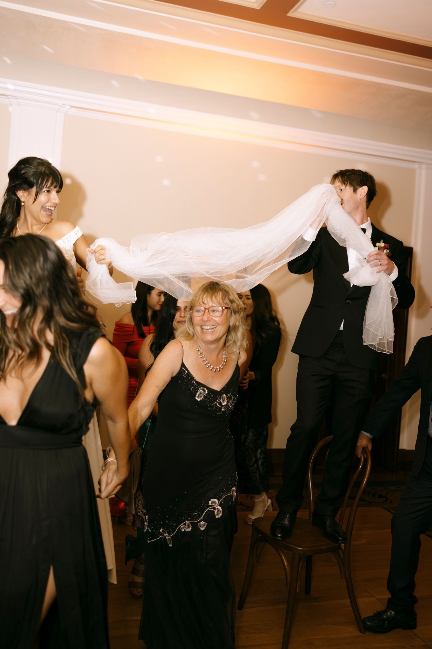 Party guests dance and twirl on a dance floor during an indoor celebration.