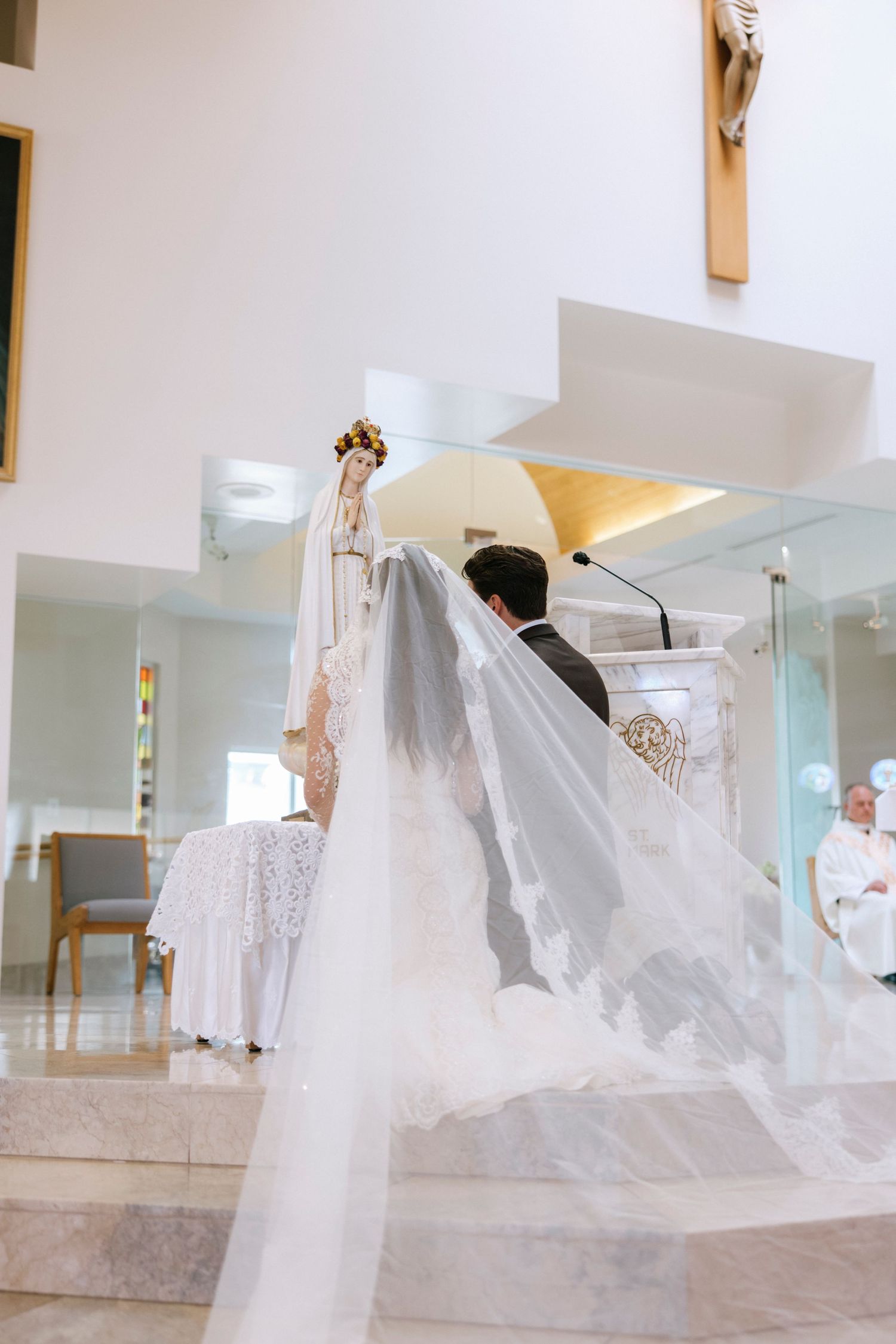 Side view of wedding couple at church altar with flowing white veil.