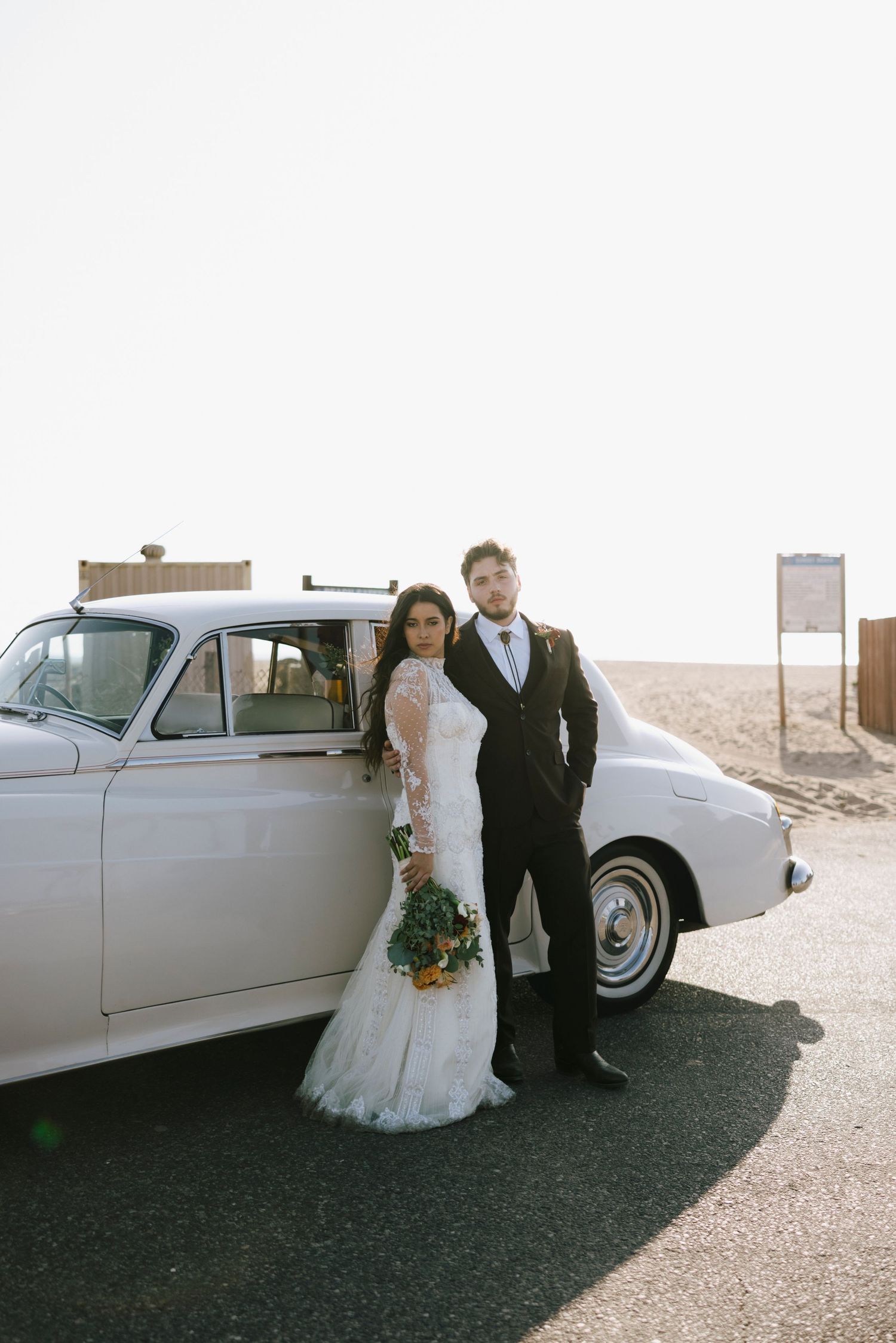 Elegant wedding photos featuring a vintage white car in a desert setting.