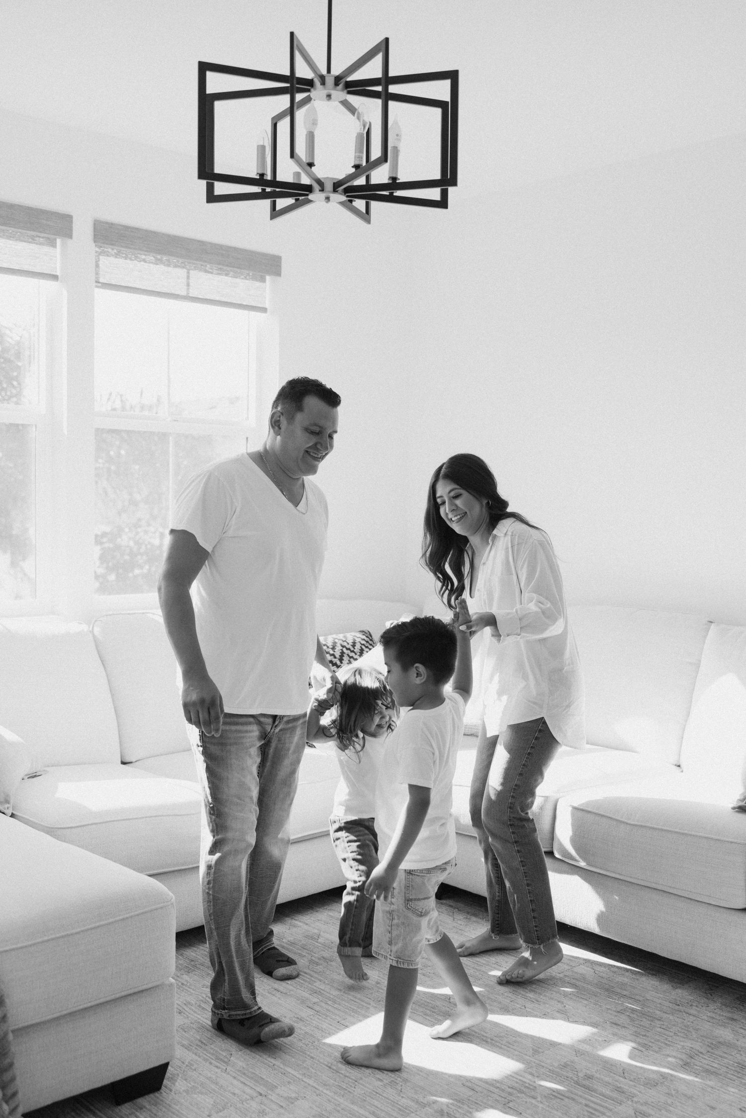 Black and white photo of family playing in a bright, modern living space.
