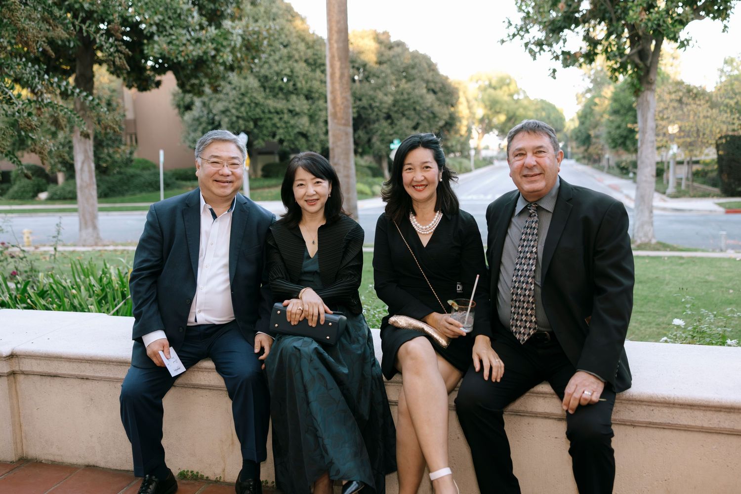 Group photo of wedding guests gathered outdoors in formal attire.
