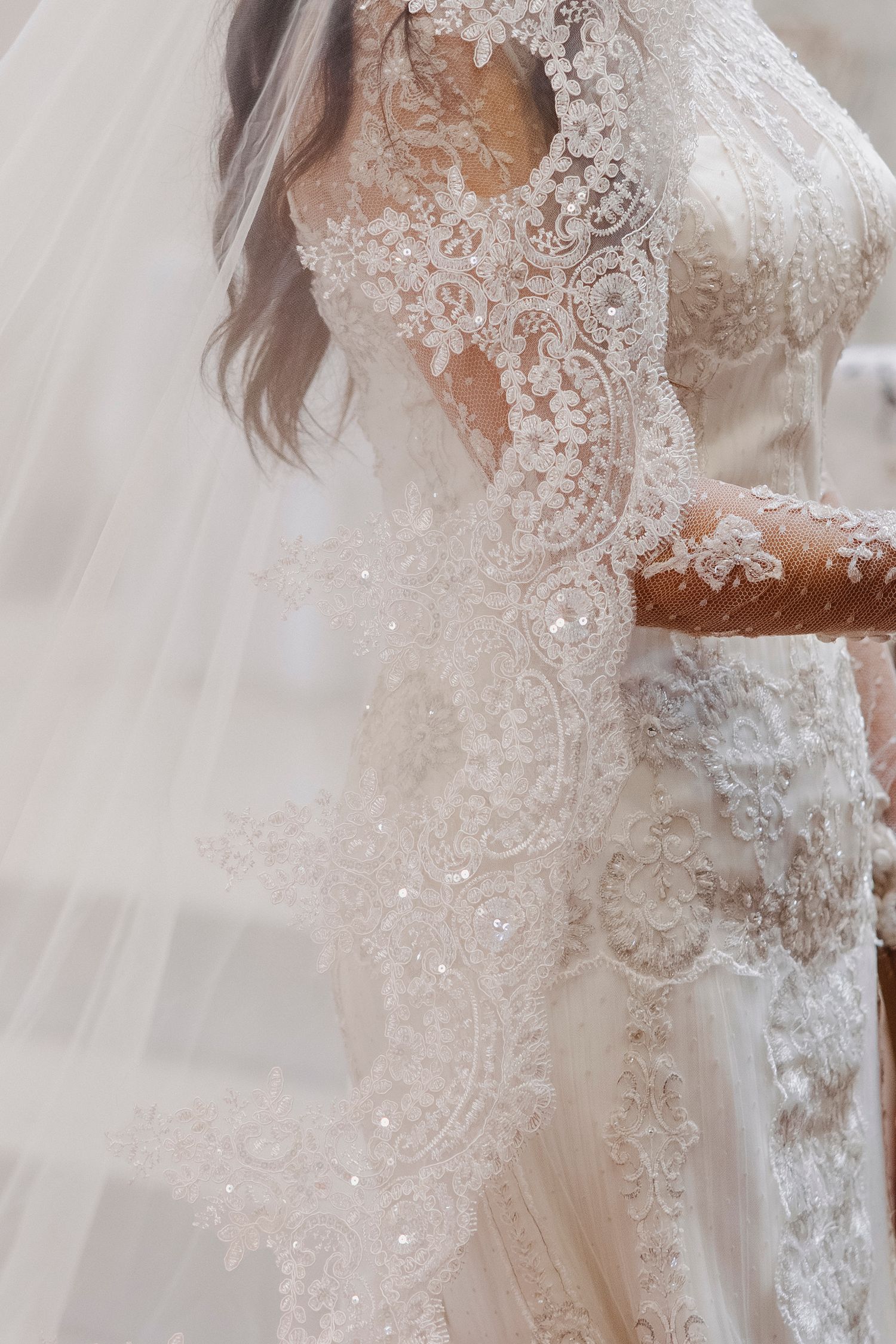 Intricate white lace and beading details on a wedding dress veil.