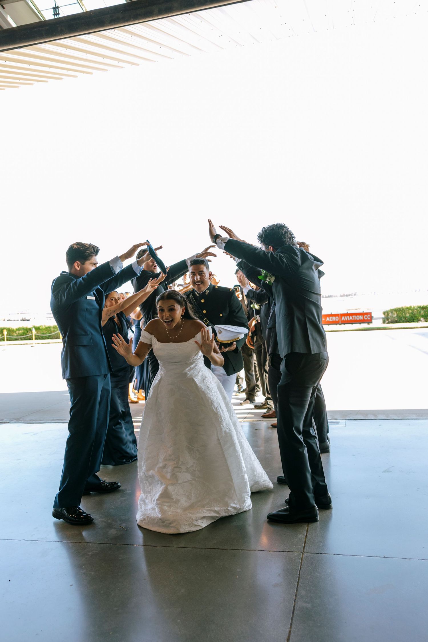 Wedding party performs synchronized dance moves in a spacious venue.
