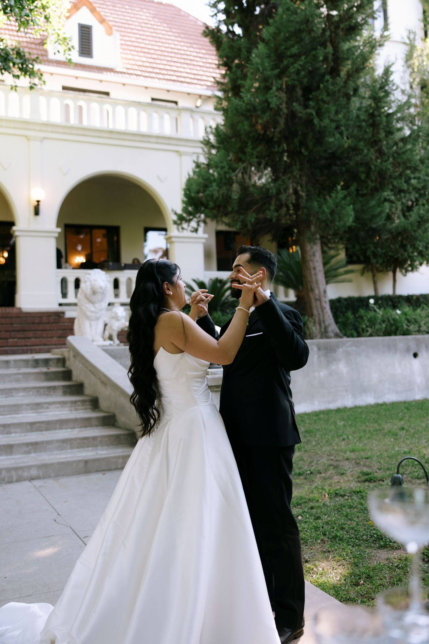 Wedding celebration outside a classic white building with arched architecture.