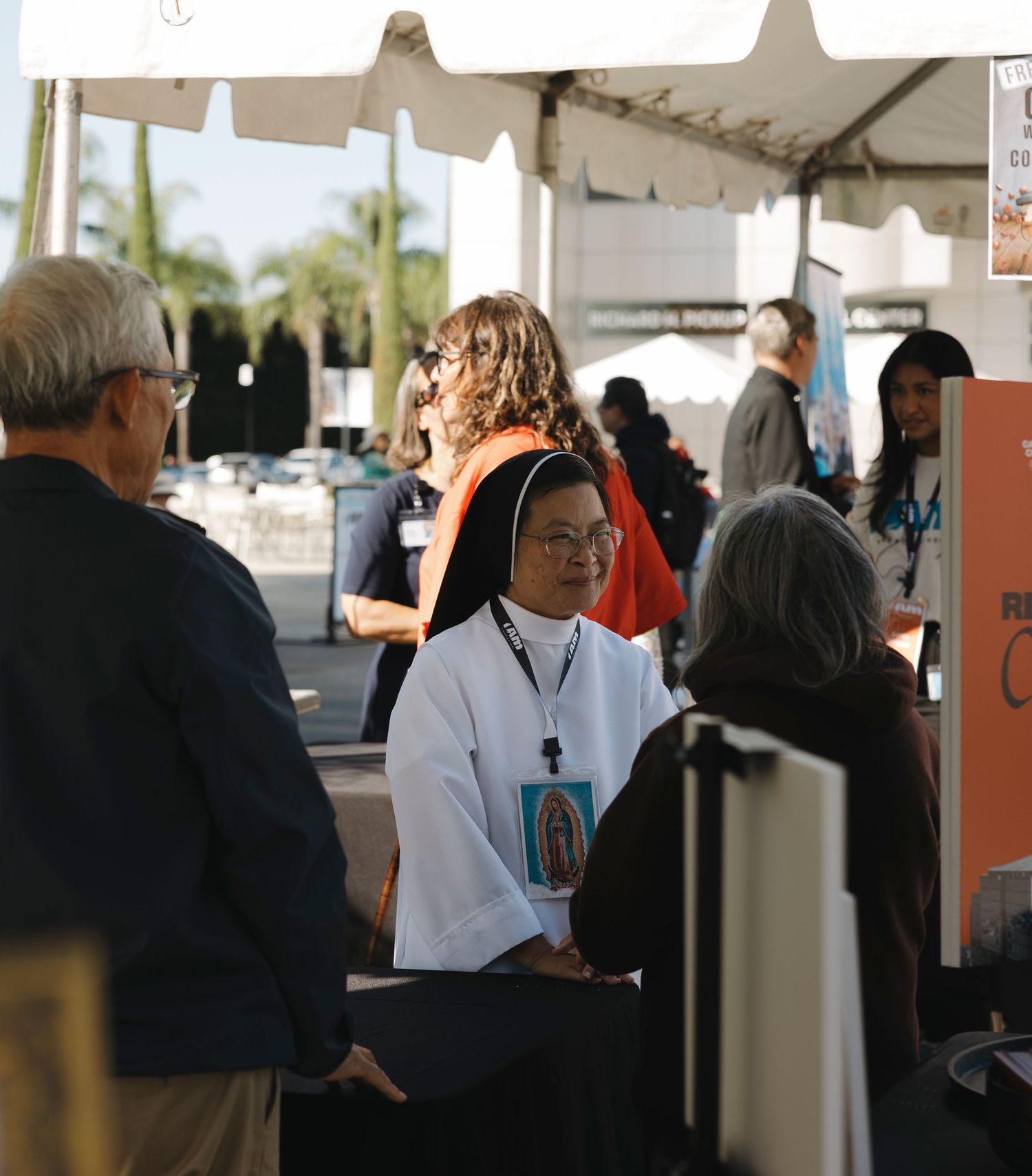 People gathering under white tents at a community event.
