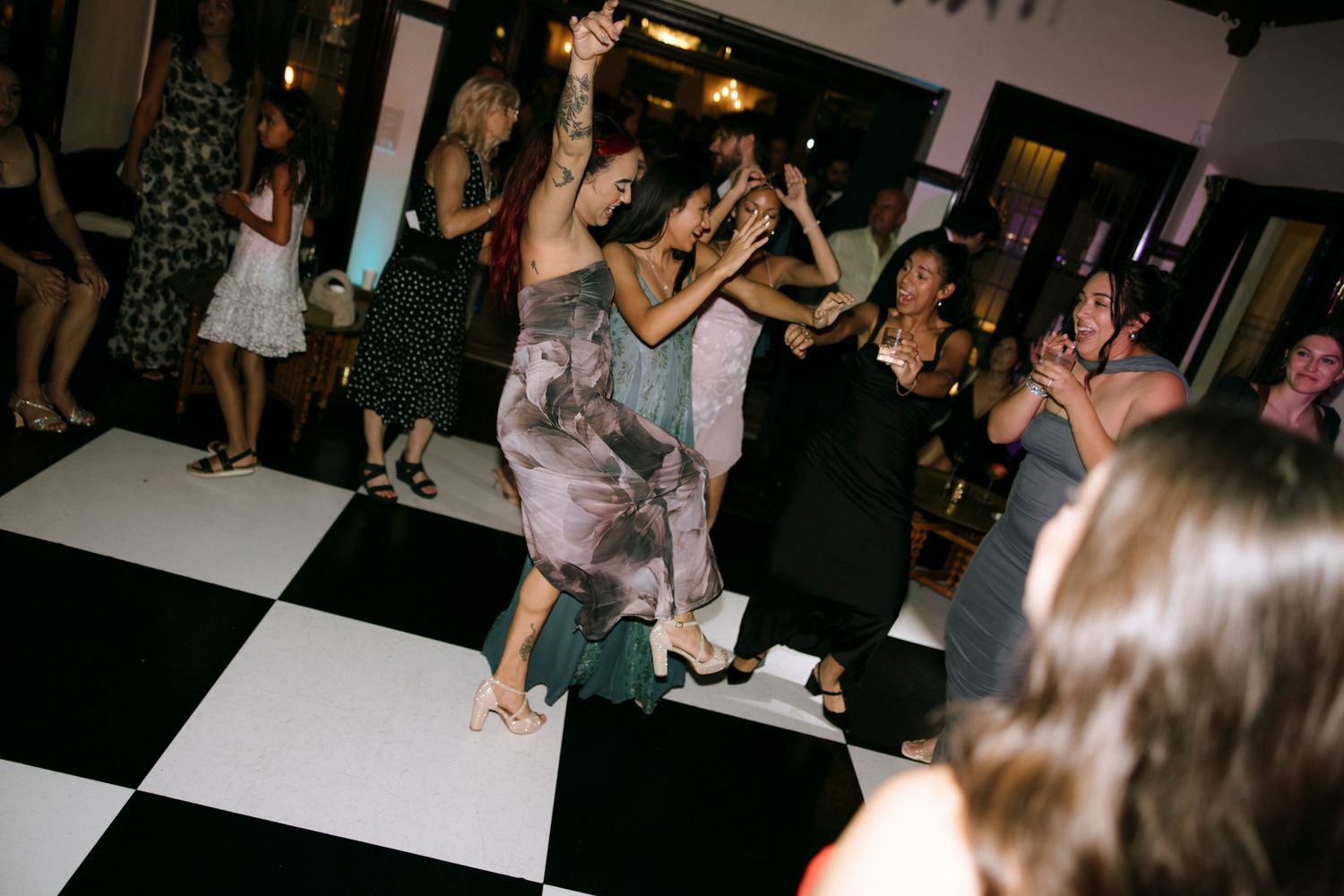 Wedding guests dancing and celebrating on a black and white checkered dance floor.