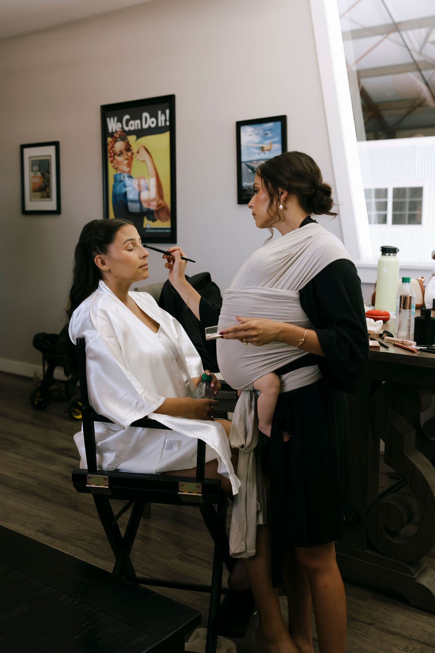 Makeup artist applies cosmetics to client in salon chair during preparation session.