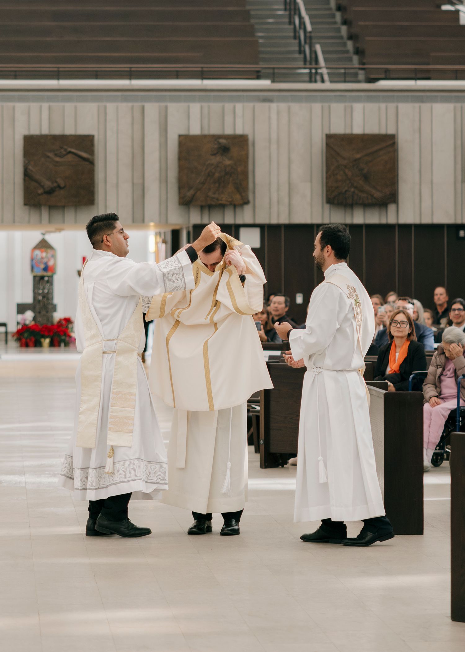 Group of clergy members in white robes gathered in a formal ceremony space.