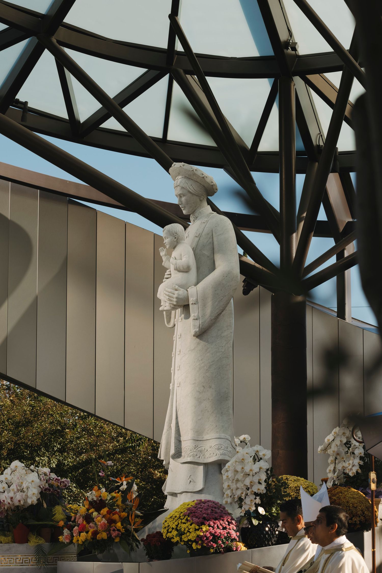 Large white religious statues displayed under an architectural structure with floral decorations.