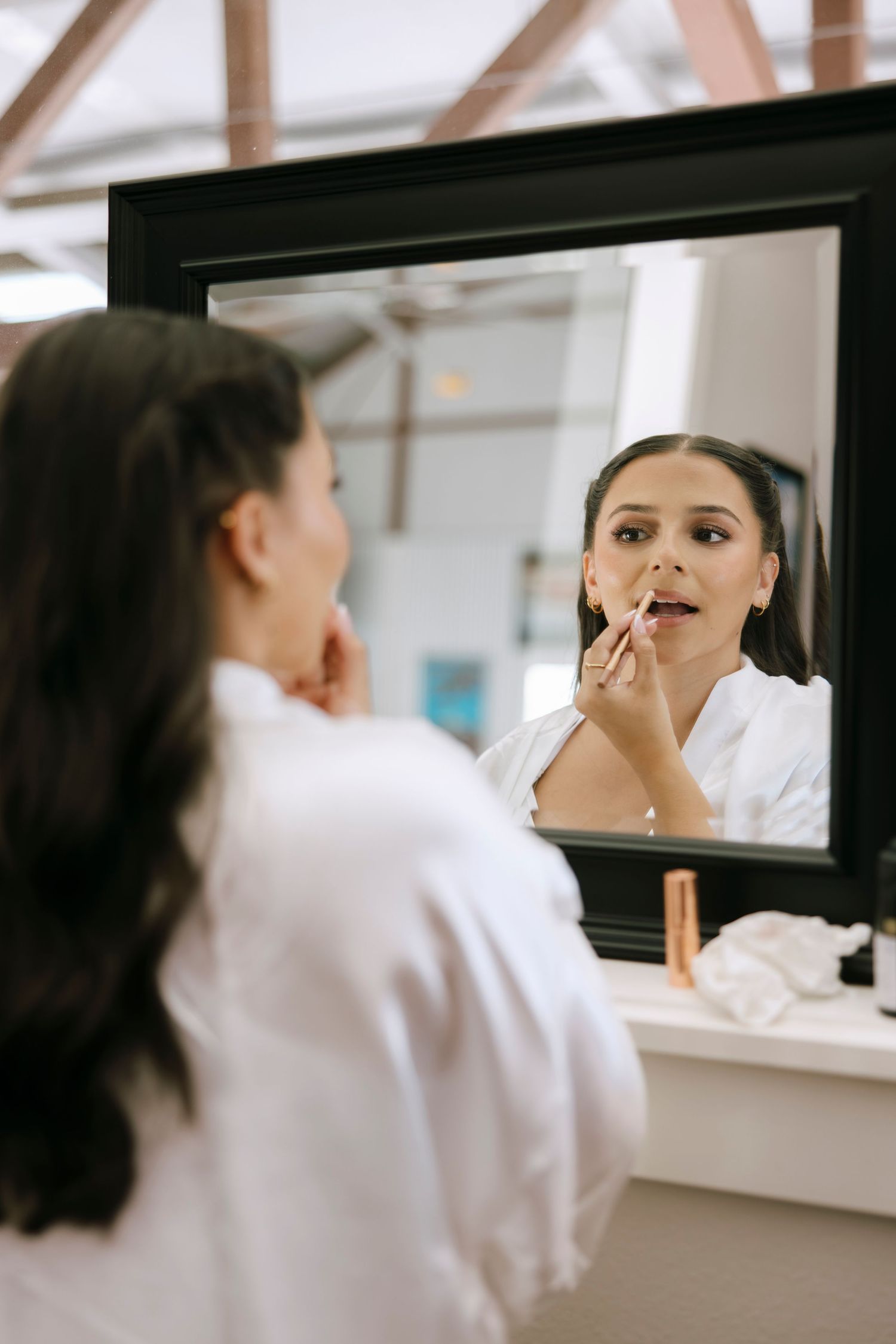 Close-up shots of makeup application being done in mirror reflection.