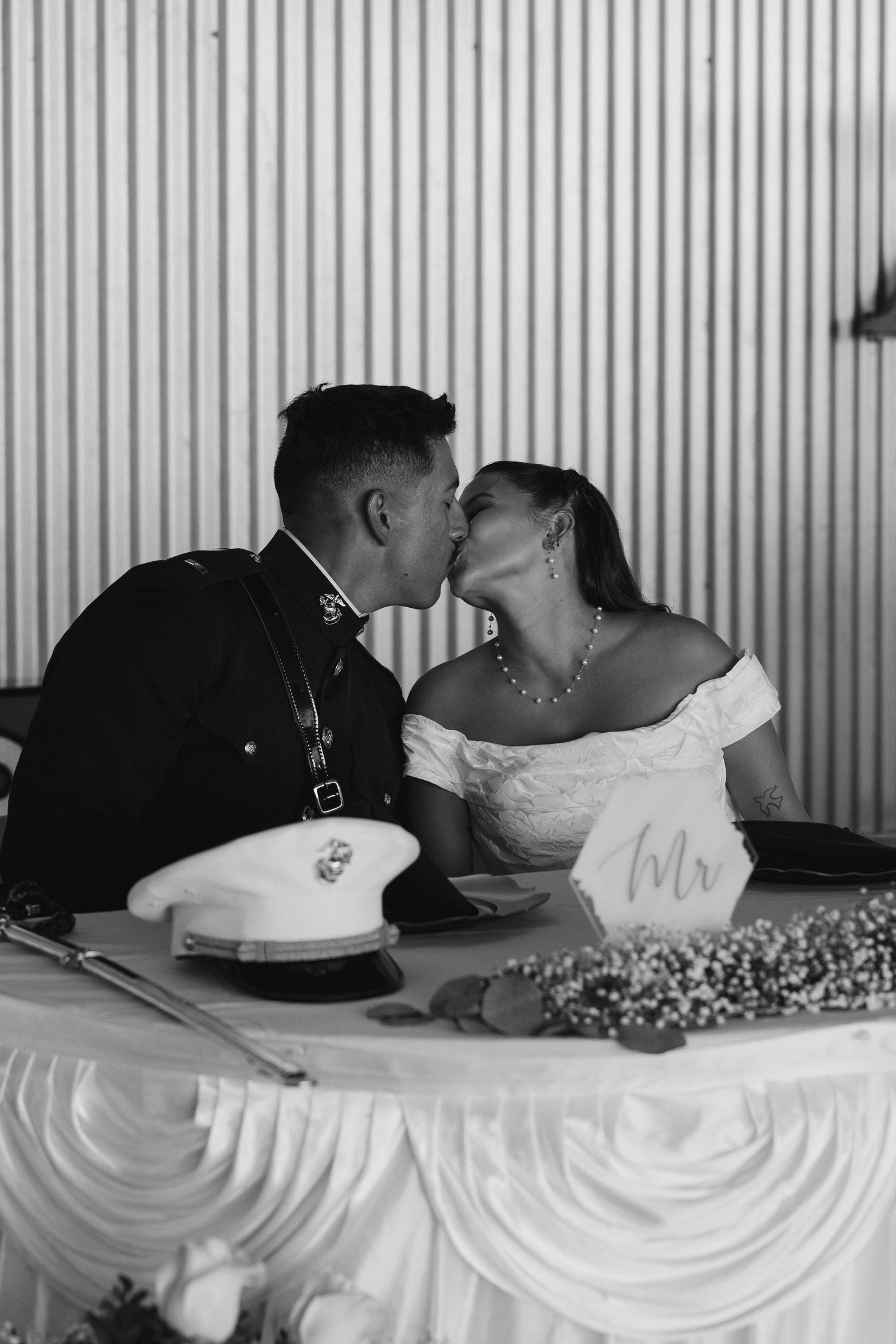 Black and white photo captures romantic moment at wedding reception table.