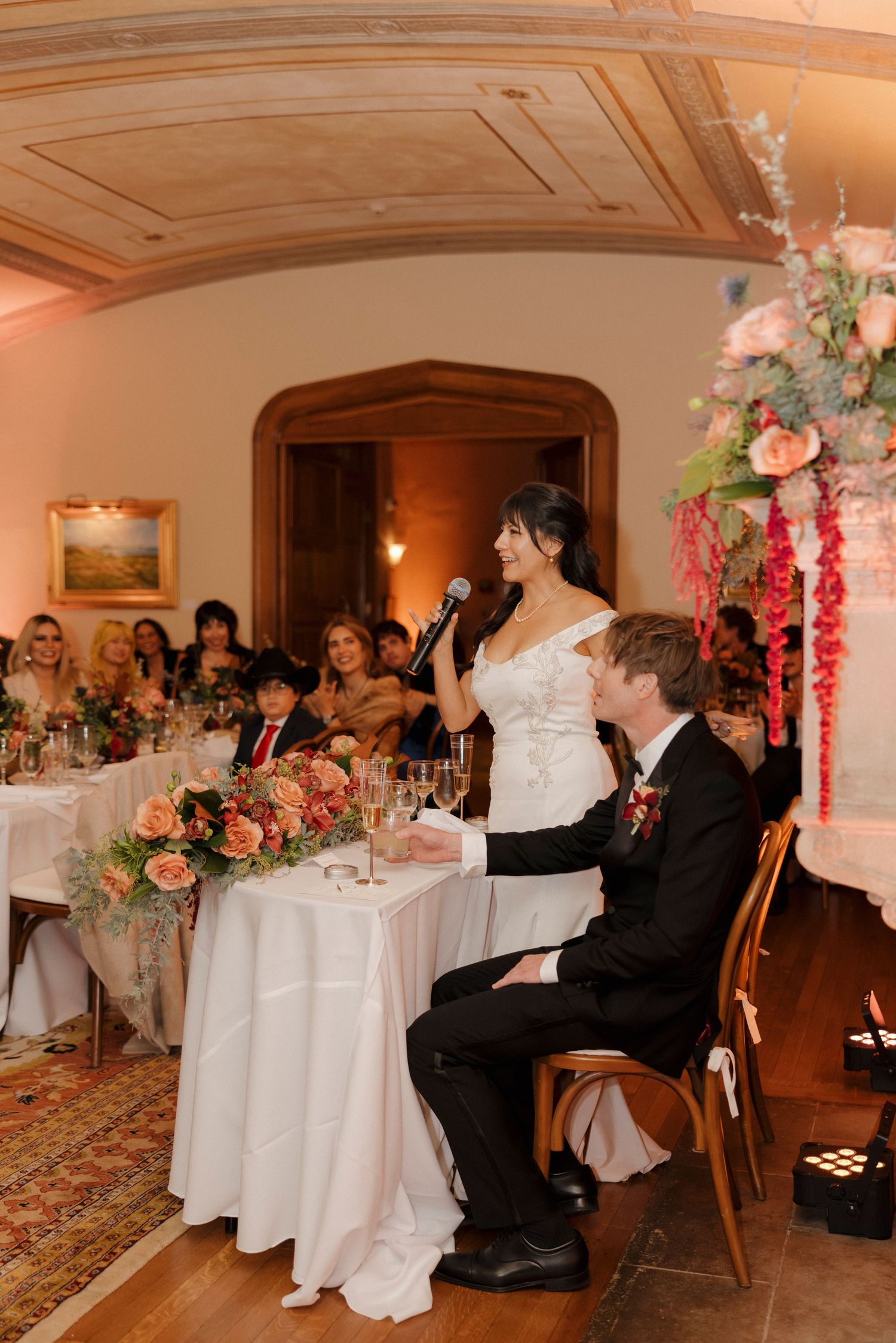 Wedding reception dining scene with decorated tables and floral centerpieces.