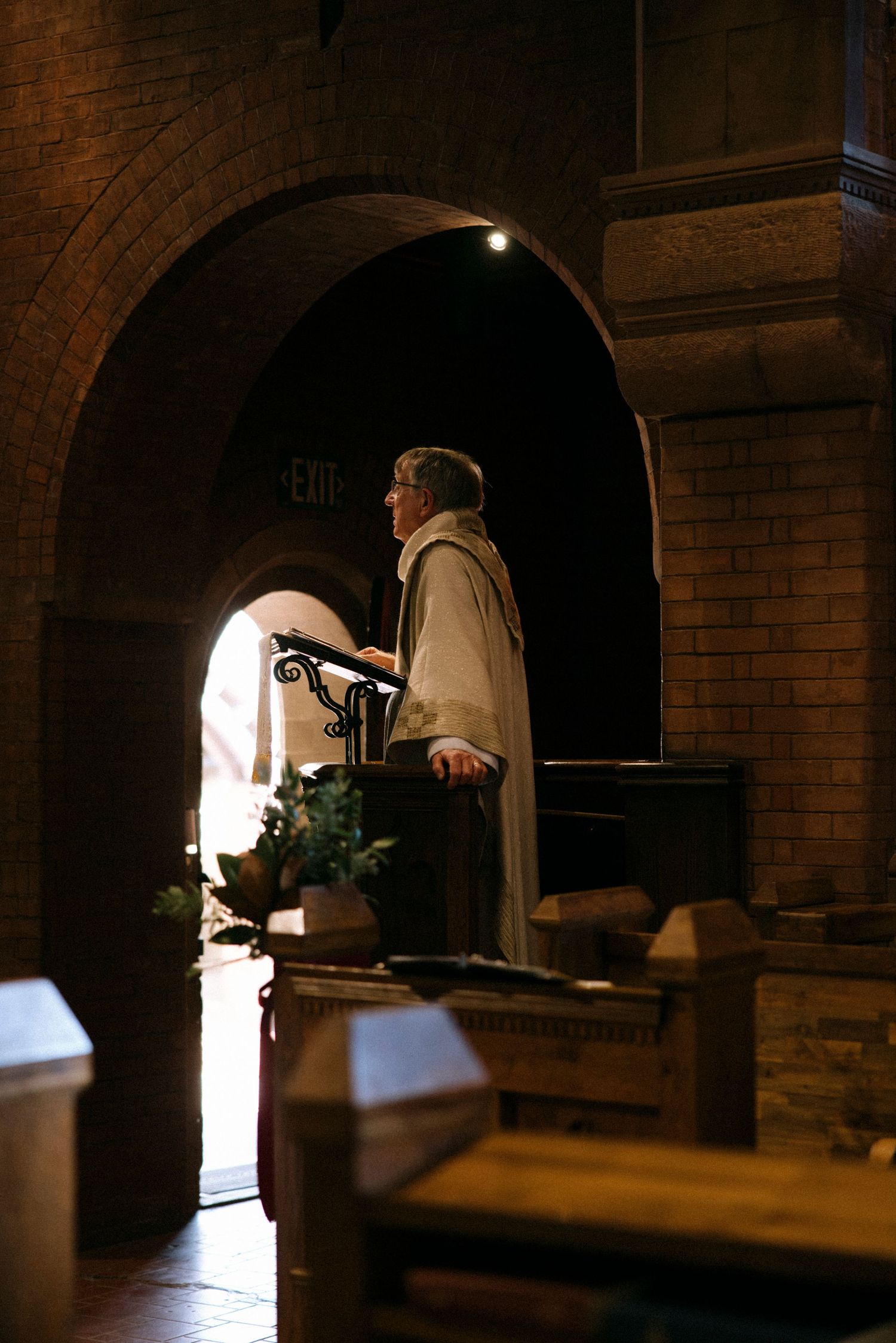 Silhouetted figures in church archway during wedding ceremony.