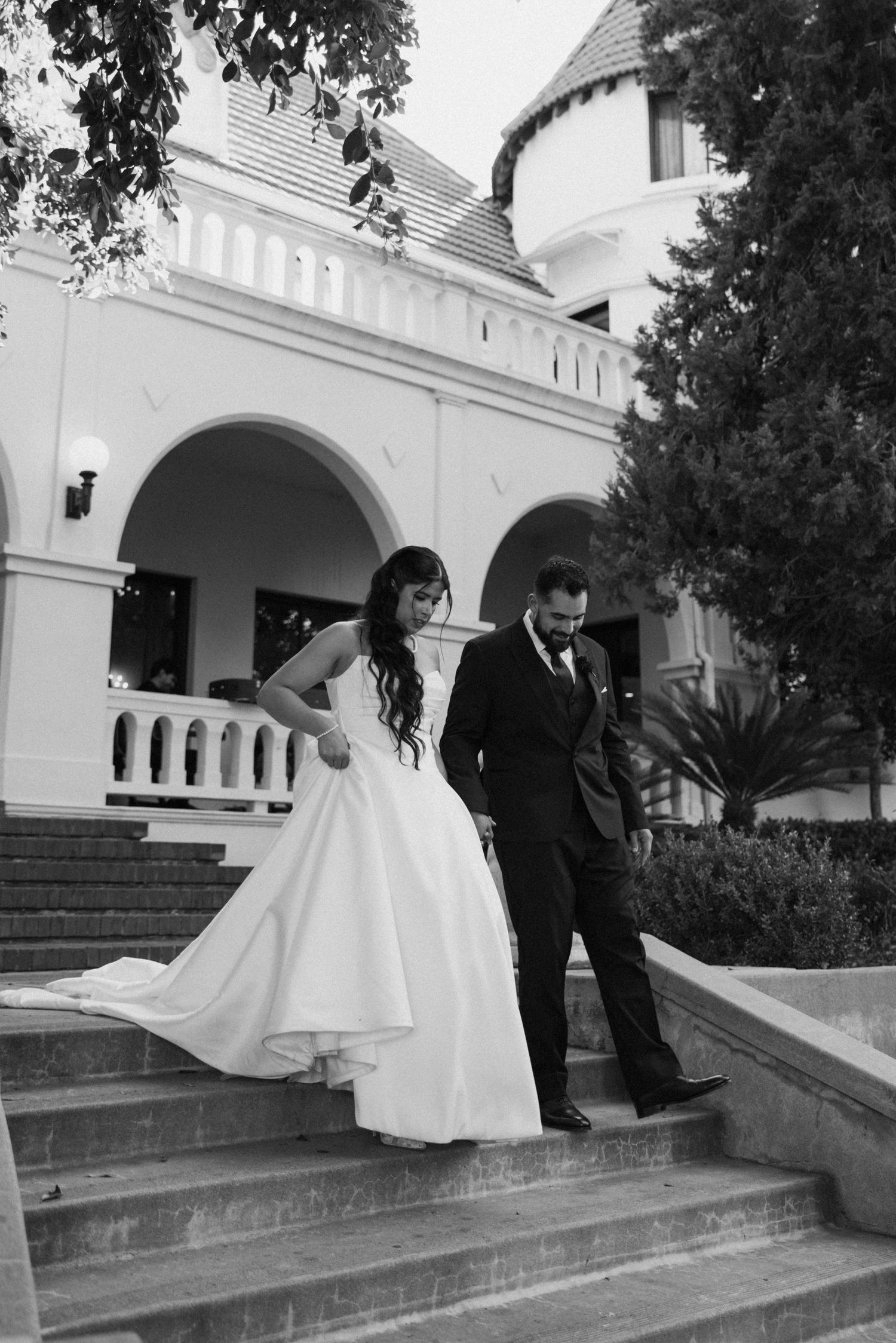 Elegant white building with arched walkway and brick steps in black and white.