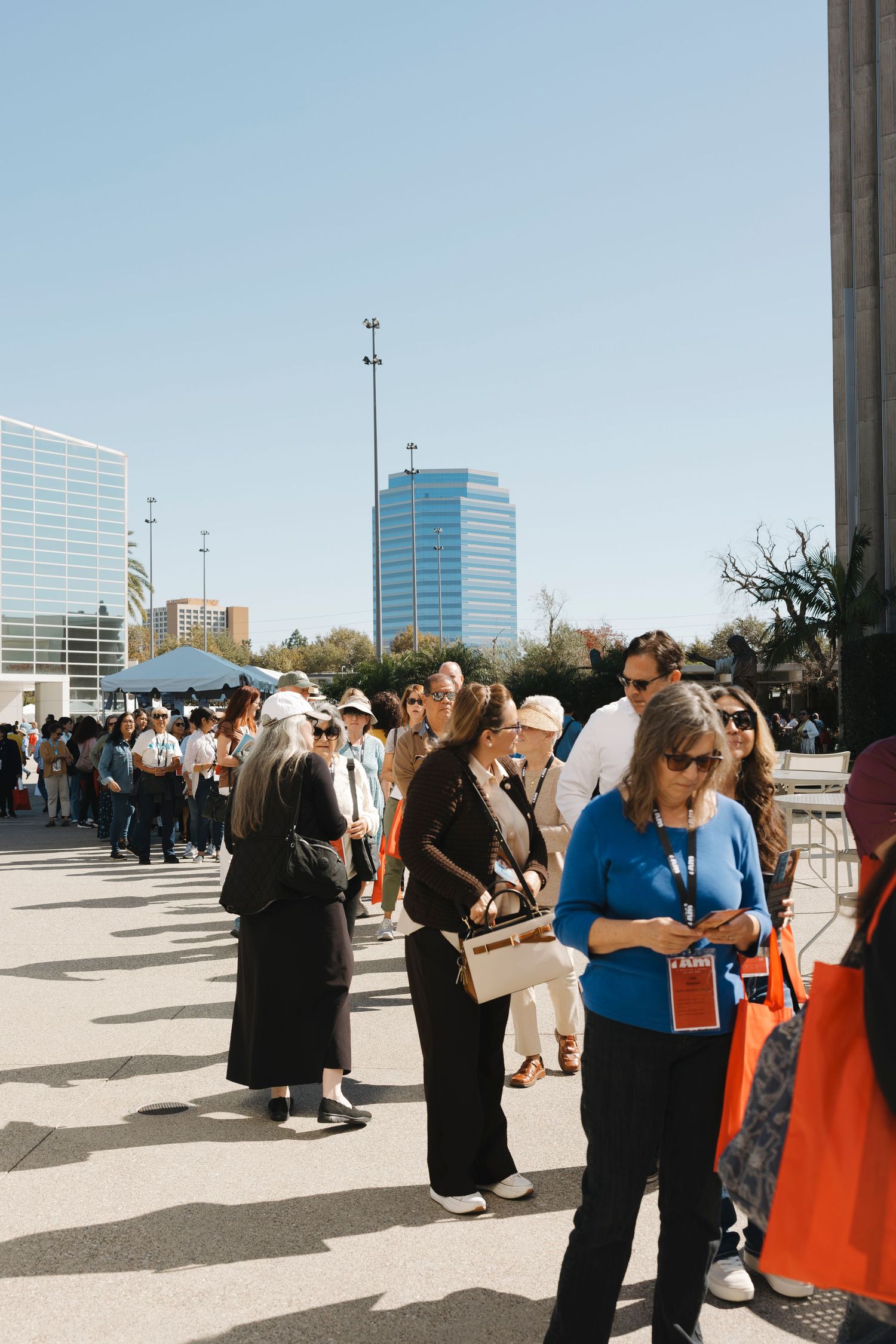 People socialize outdoors with modern office buildings visible in the background.