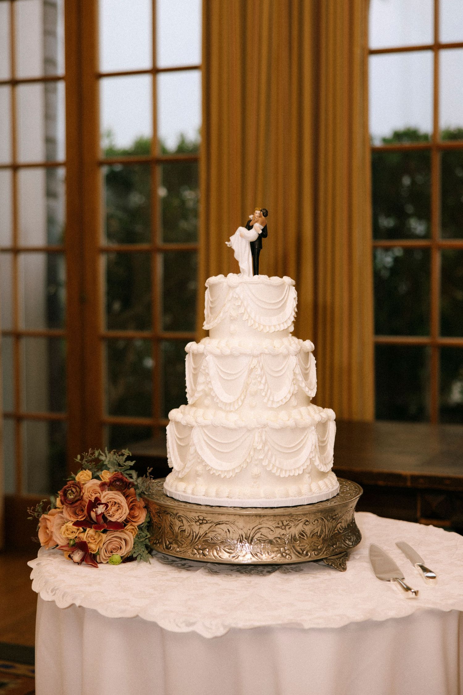 Multiple elegant white wedding cakes displayed on tables with floral decorations at a reception venue.