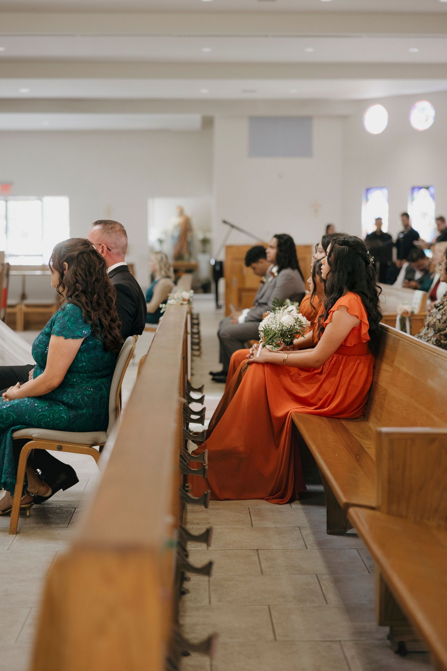 Wedding guests seated in wooden church pews during ceremony.
