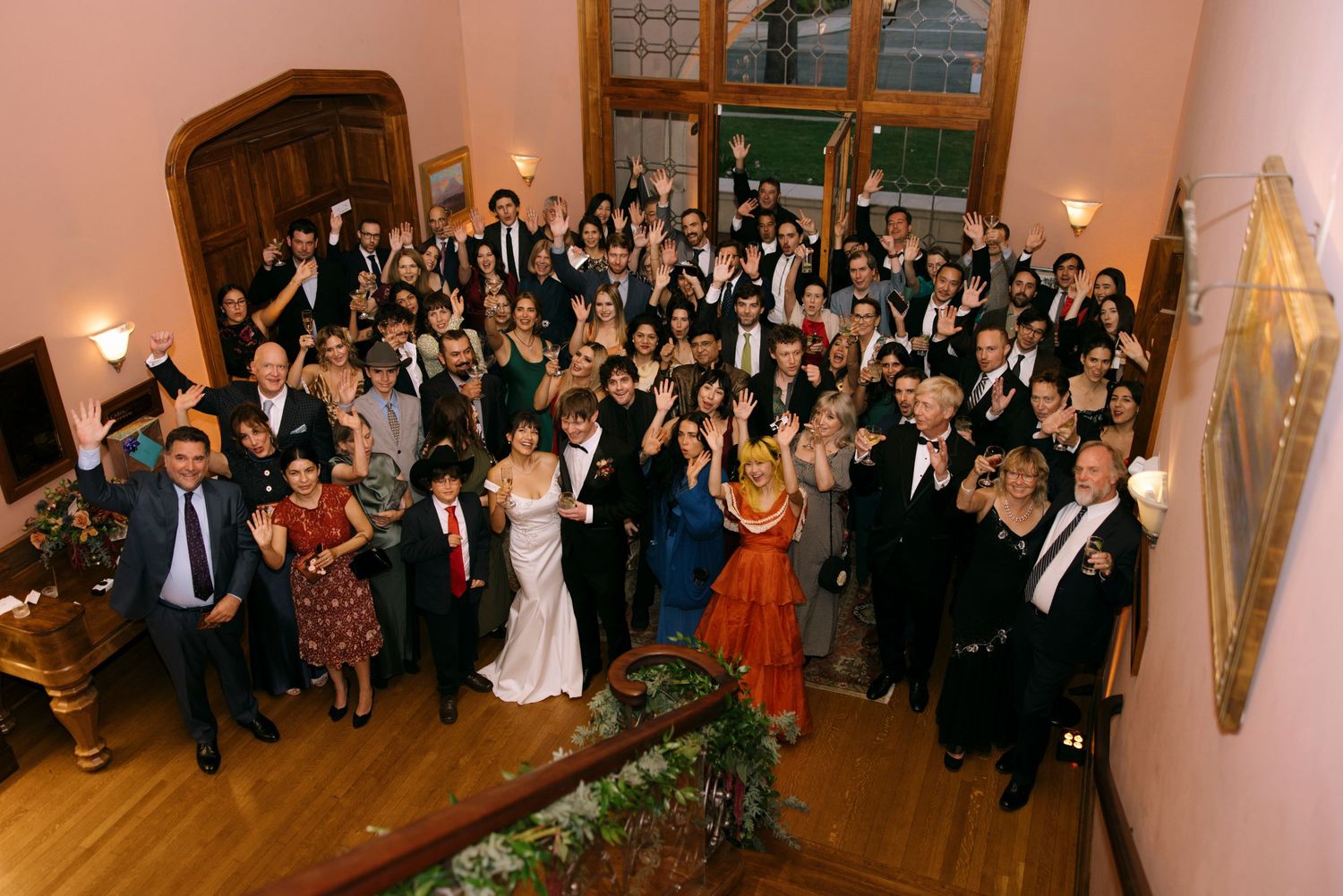 Large group of wedding guests dancing and celebrating in an elegant ballroom setting.