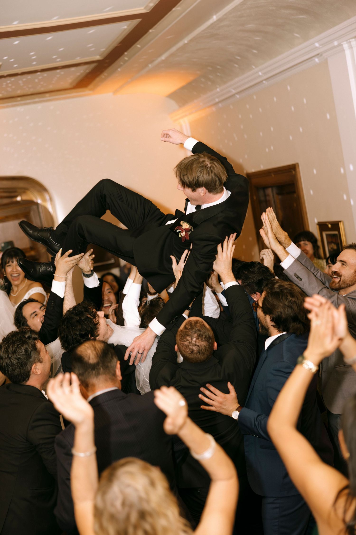 Crowd lifts and carries someone during an energetic dance celebration at an indoor venue.