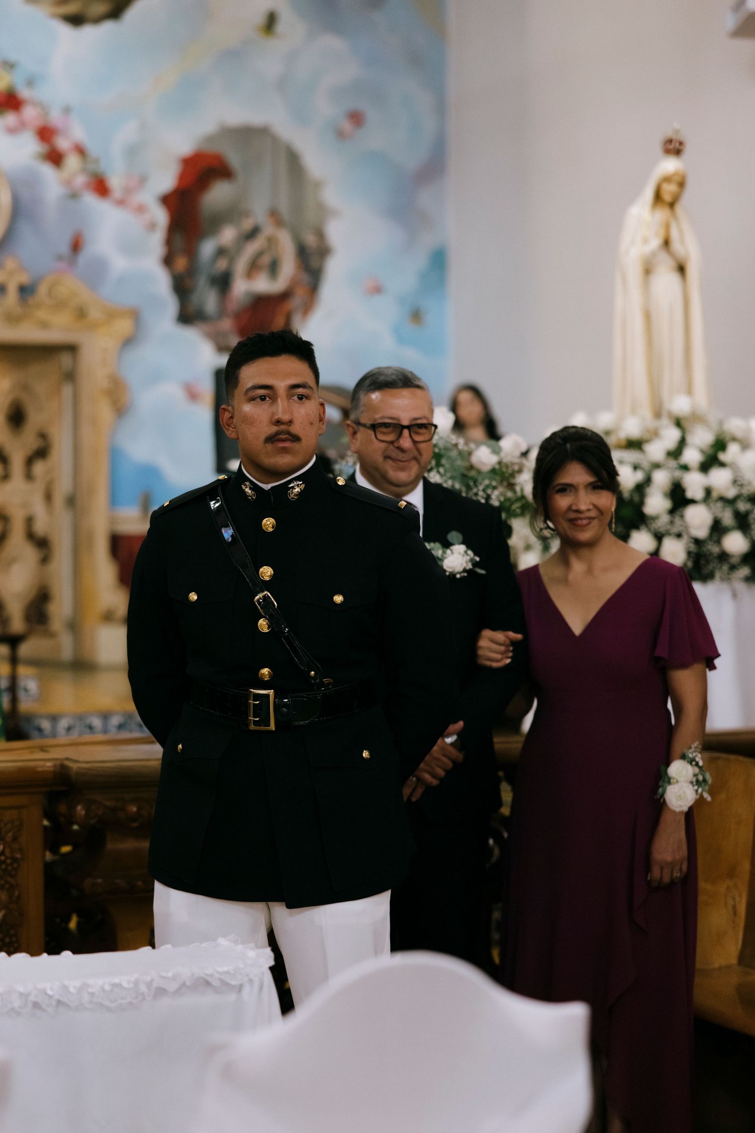 A formal ceremony in a church with floral arrangements and painted ceiling murals.