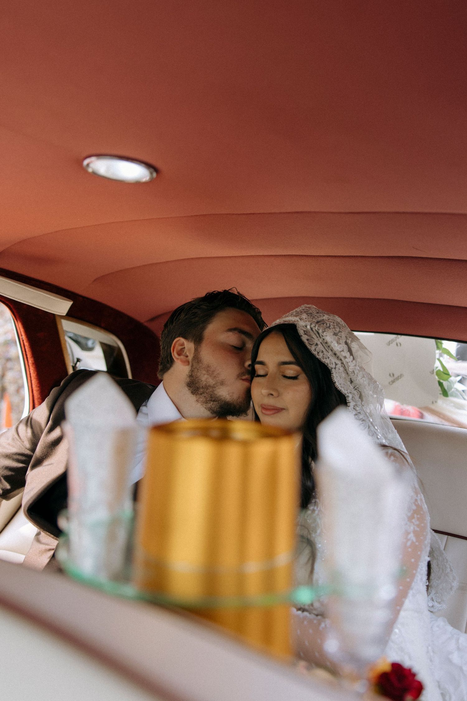 A tender moment captured inside a vintage car with warm lighting.