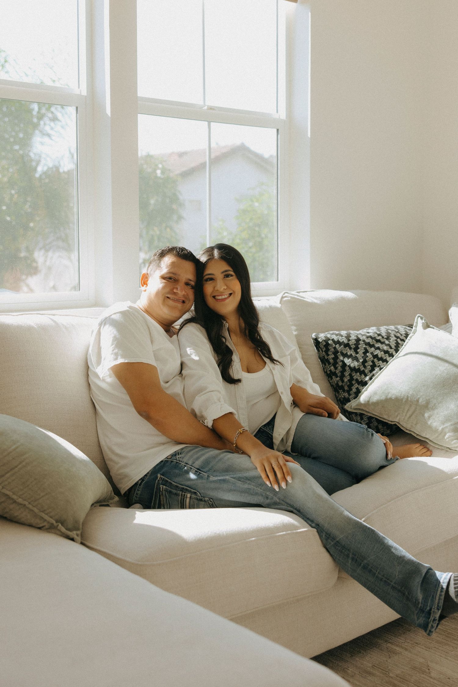 Family relaxing together on white couch in sunlit living room.