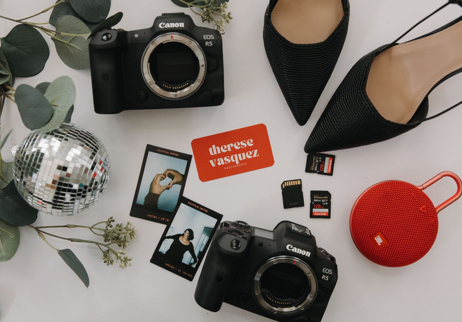 Flatlay of camera equipment and accessories arranged on white surface.