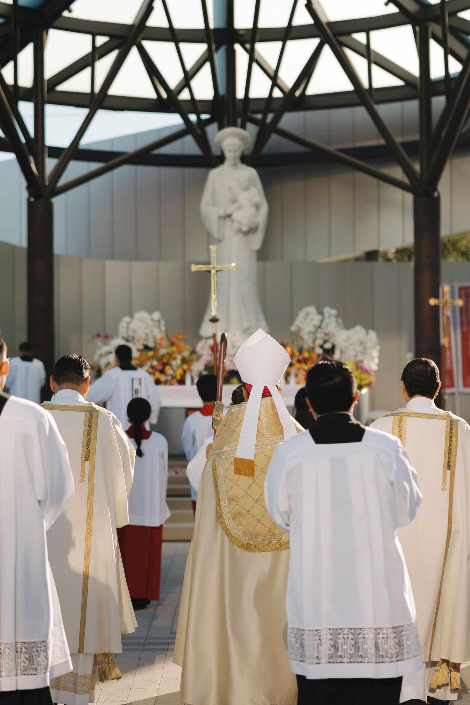 White and gold vestments hanging on display in an indoor church setting.