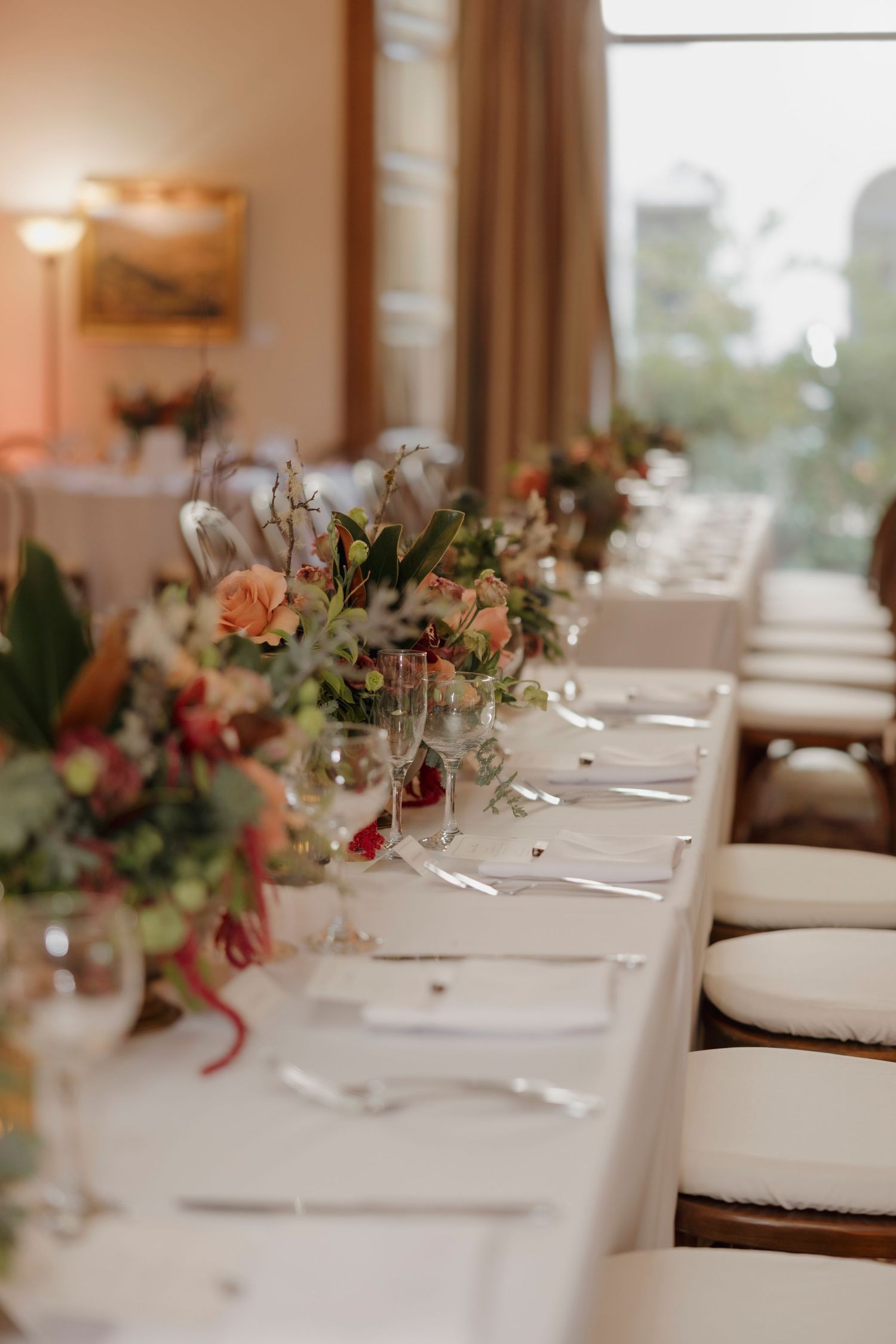 Elegant table settings with white linens and delicate floral centerpieces in a bright dining room.