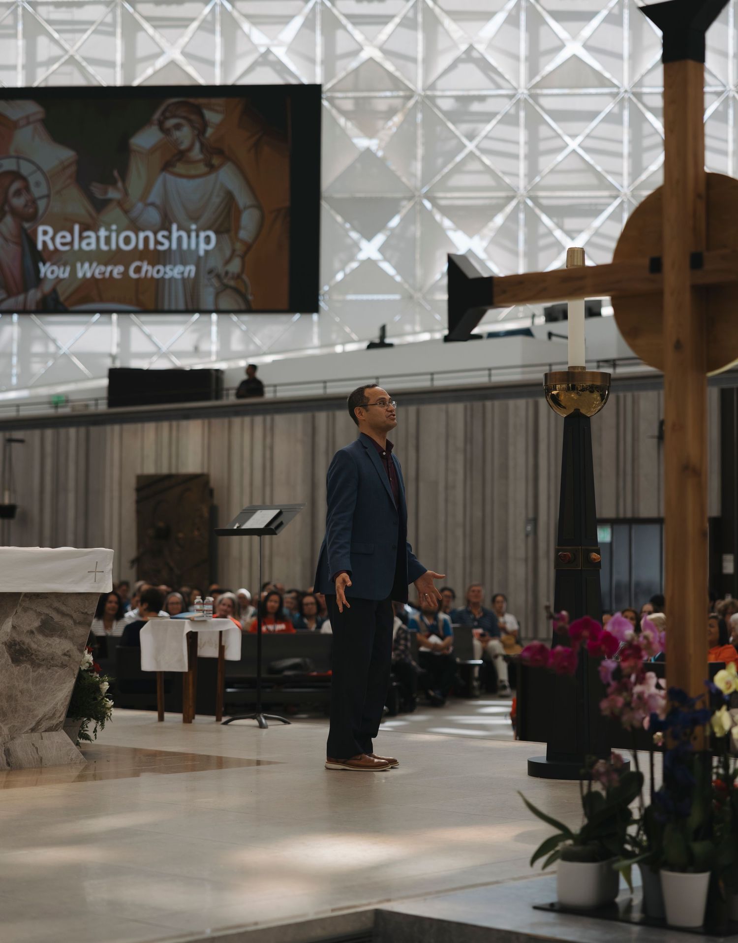 A presenter speaks on stage with a large screen displaying 'Relationship' text in a modern church setting.