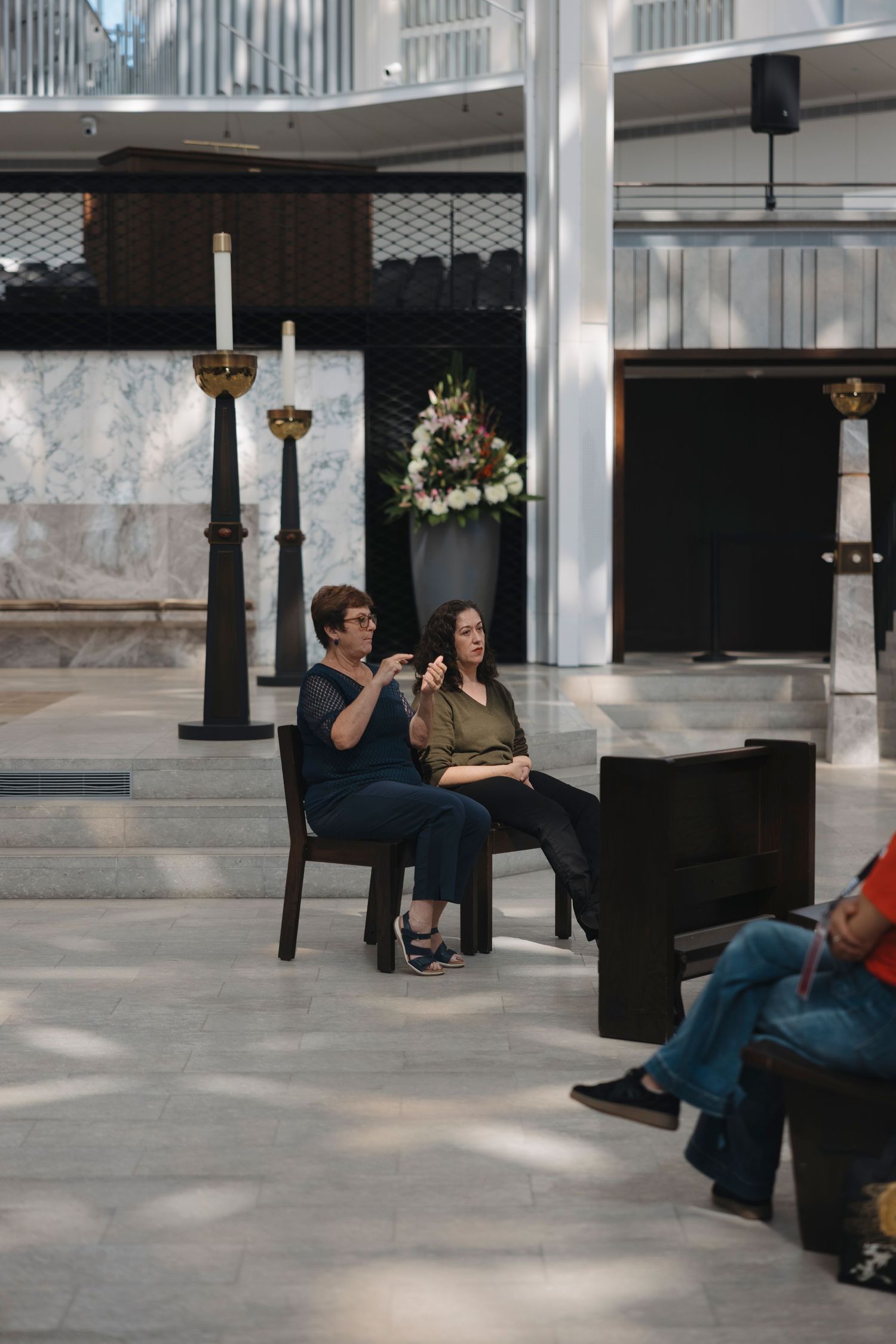 People seated near a piano in a modern church sanctuary with marble walls.