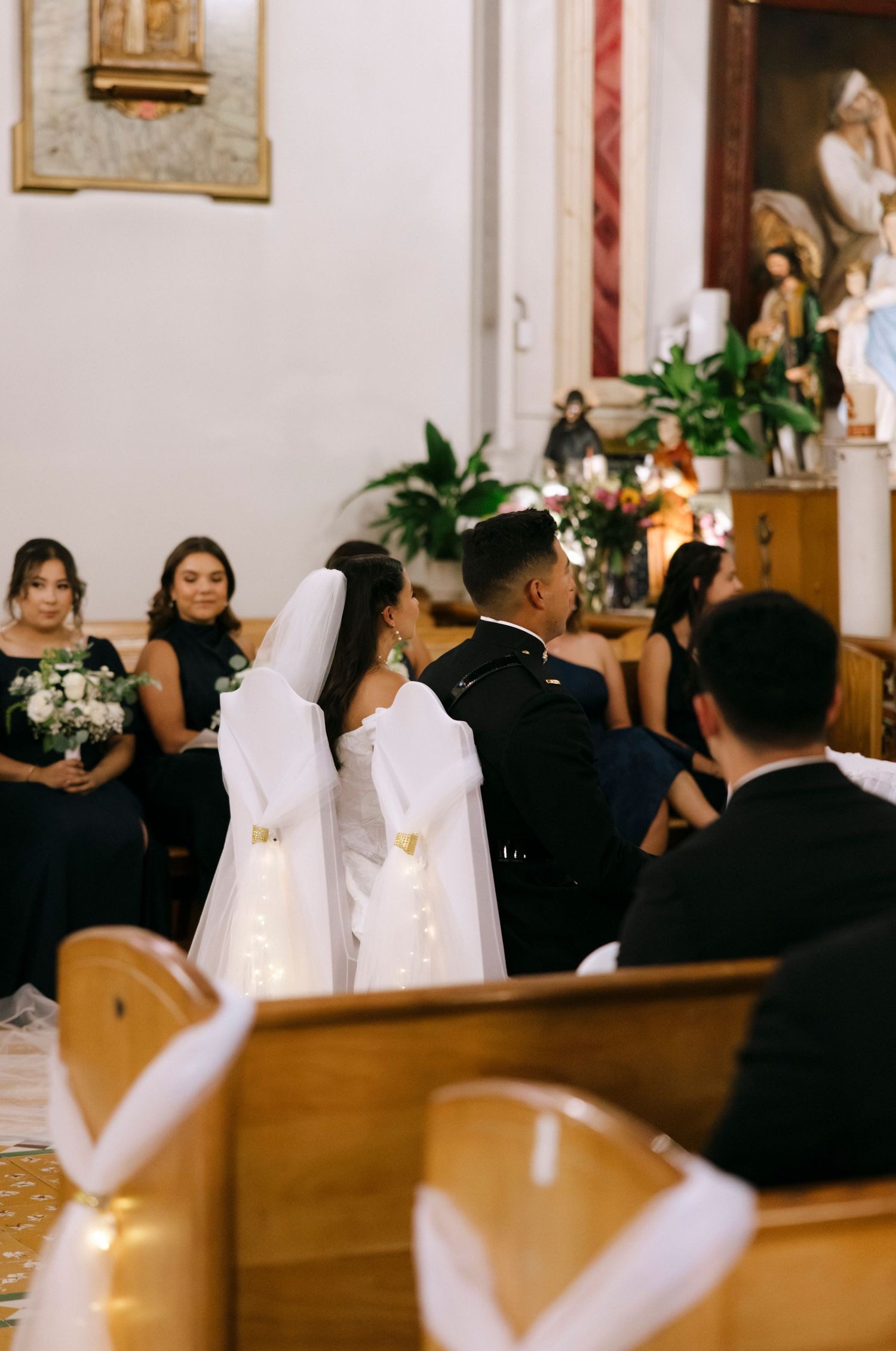 A wedding ceremony in progress inside a traditional Catholic church with religious artwork visible.
