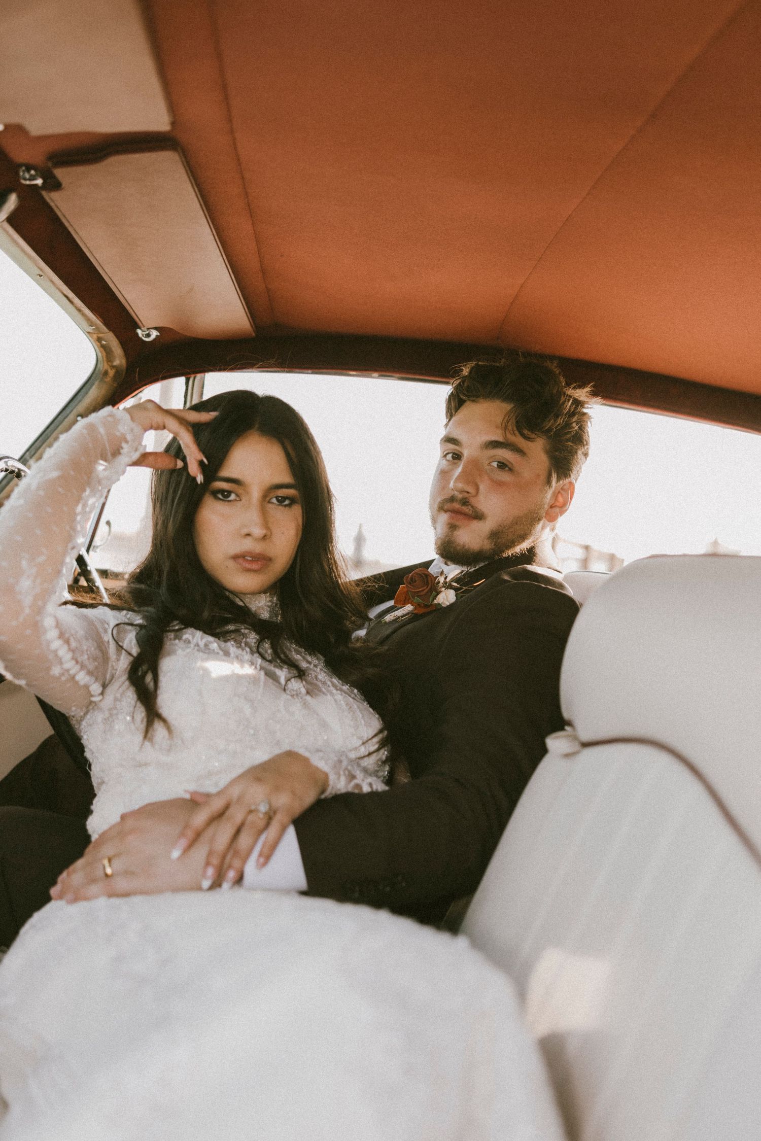 Intimate wedding couple portraits inside a vintage car with warm lighting.