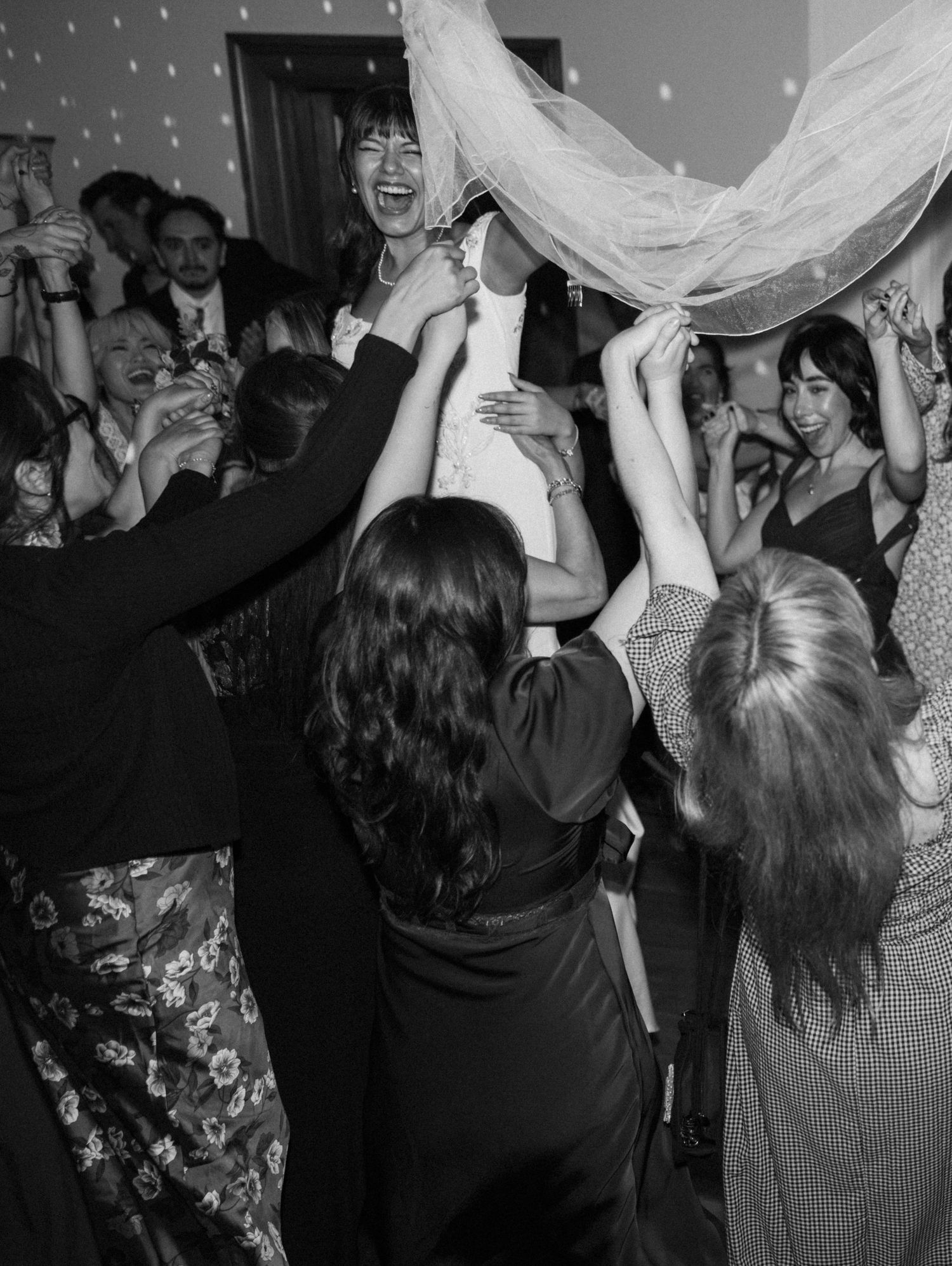 Black and white photo of guests dancing with fabric at a celebration.