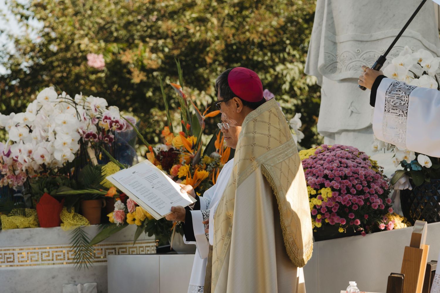 Religious ceremony setup with decorative flowers and golden-trimmed ceremonial vestments.