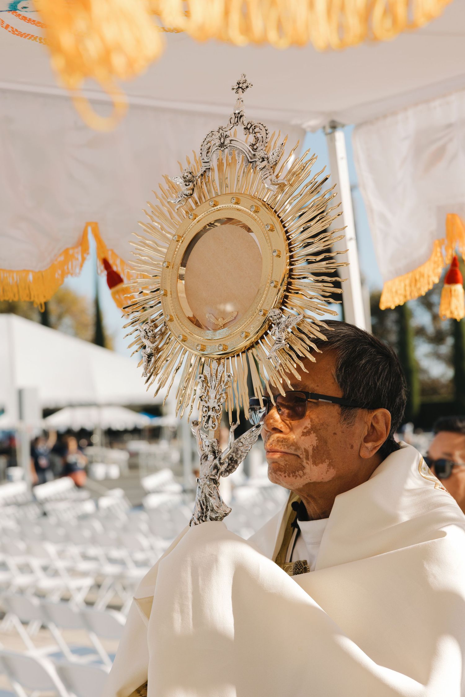 Ornate golden monstrance displayed during outdoor Catholic ceremony.
