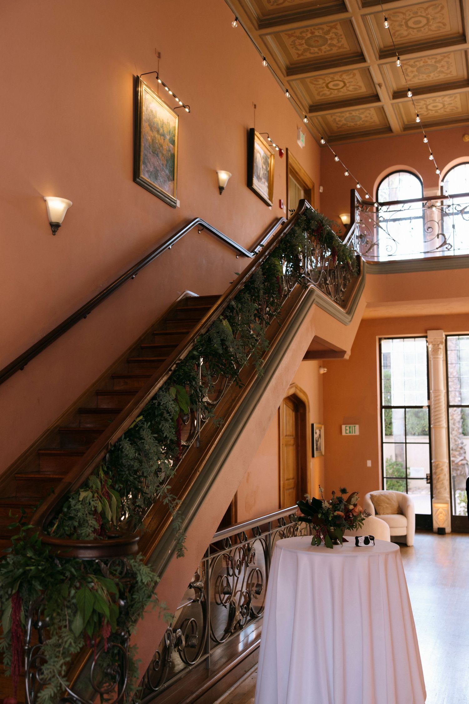 Grand staircase with decorative railings and white tablecloths in an elegant venue interior.