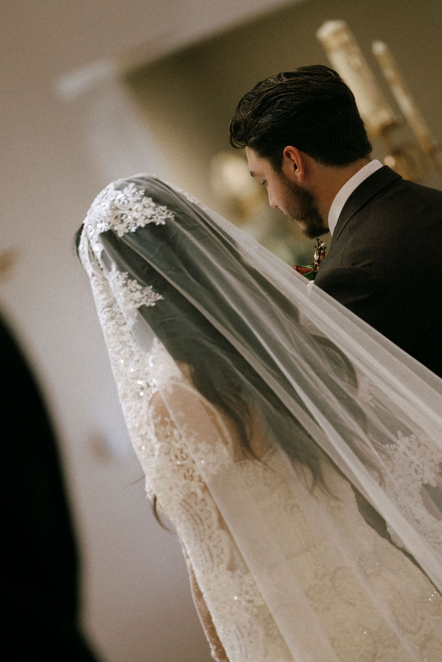 Close-up view of an ornate lace wedding veil during a church ceremony.