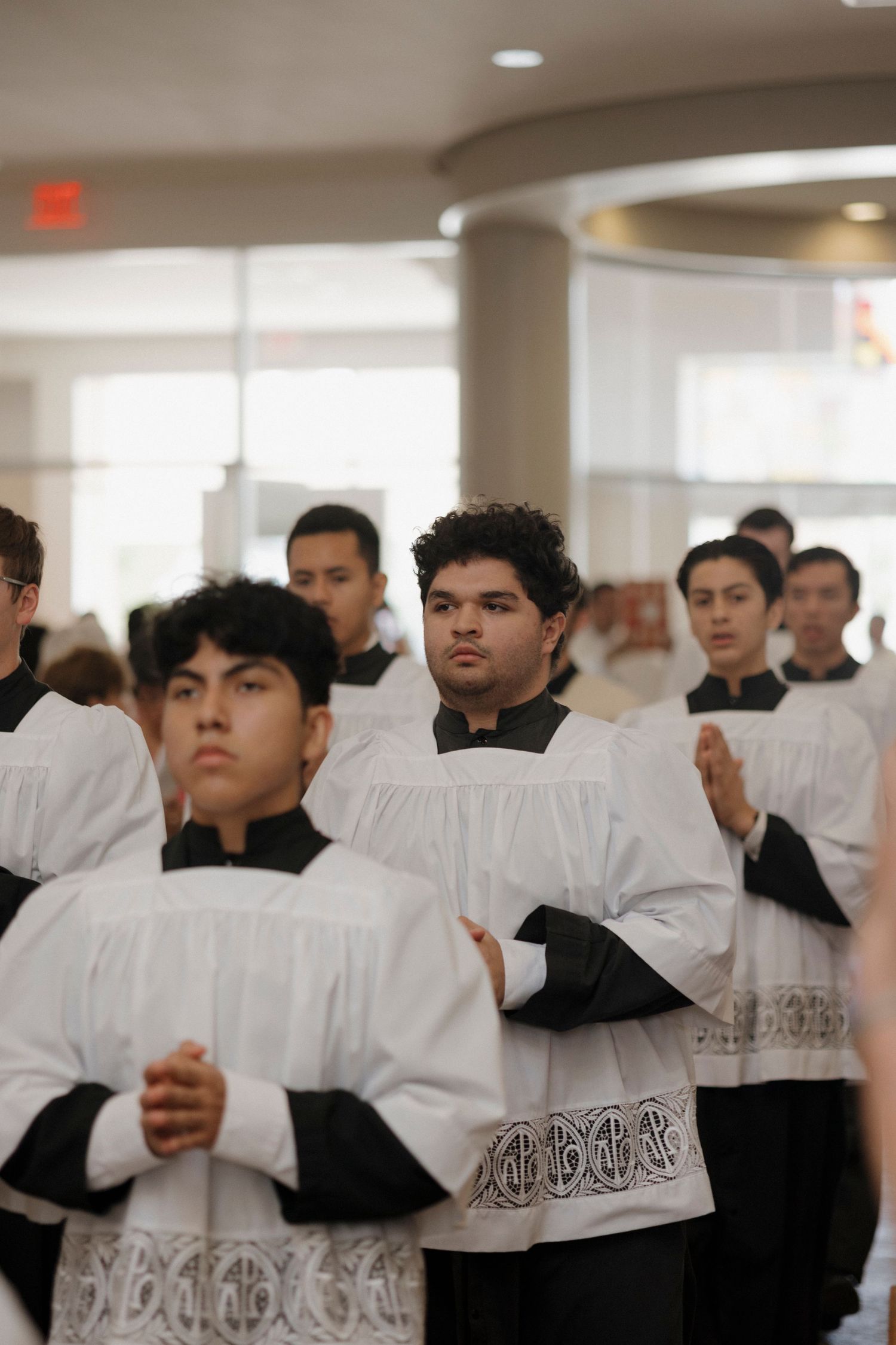 Group of people in white robes gathered in an indoor ceremony or service.