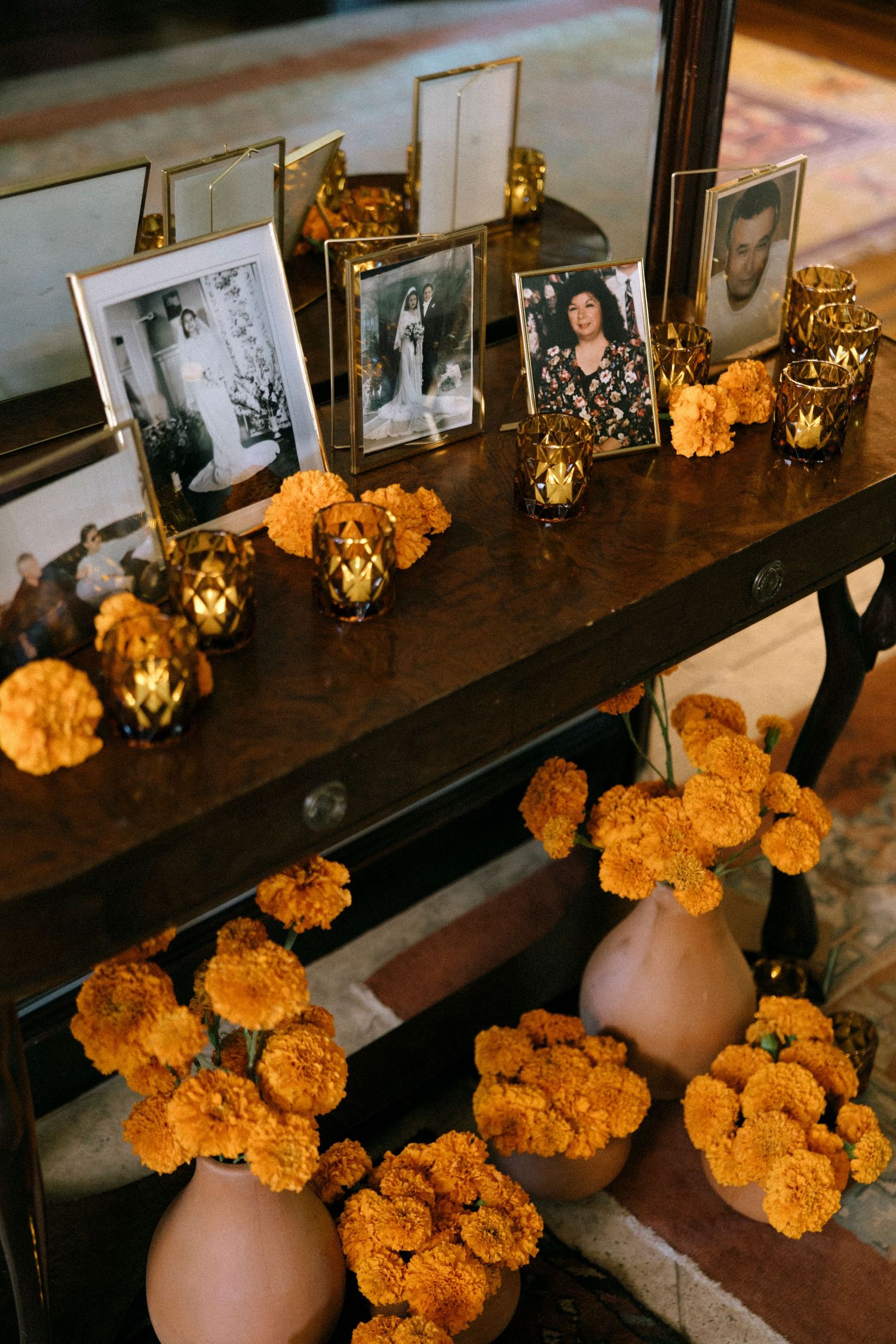 Orange marigold flowers and framed photos decorate a dark wooden table.